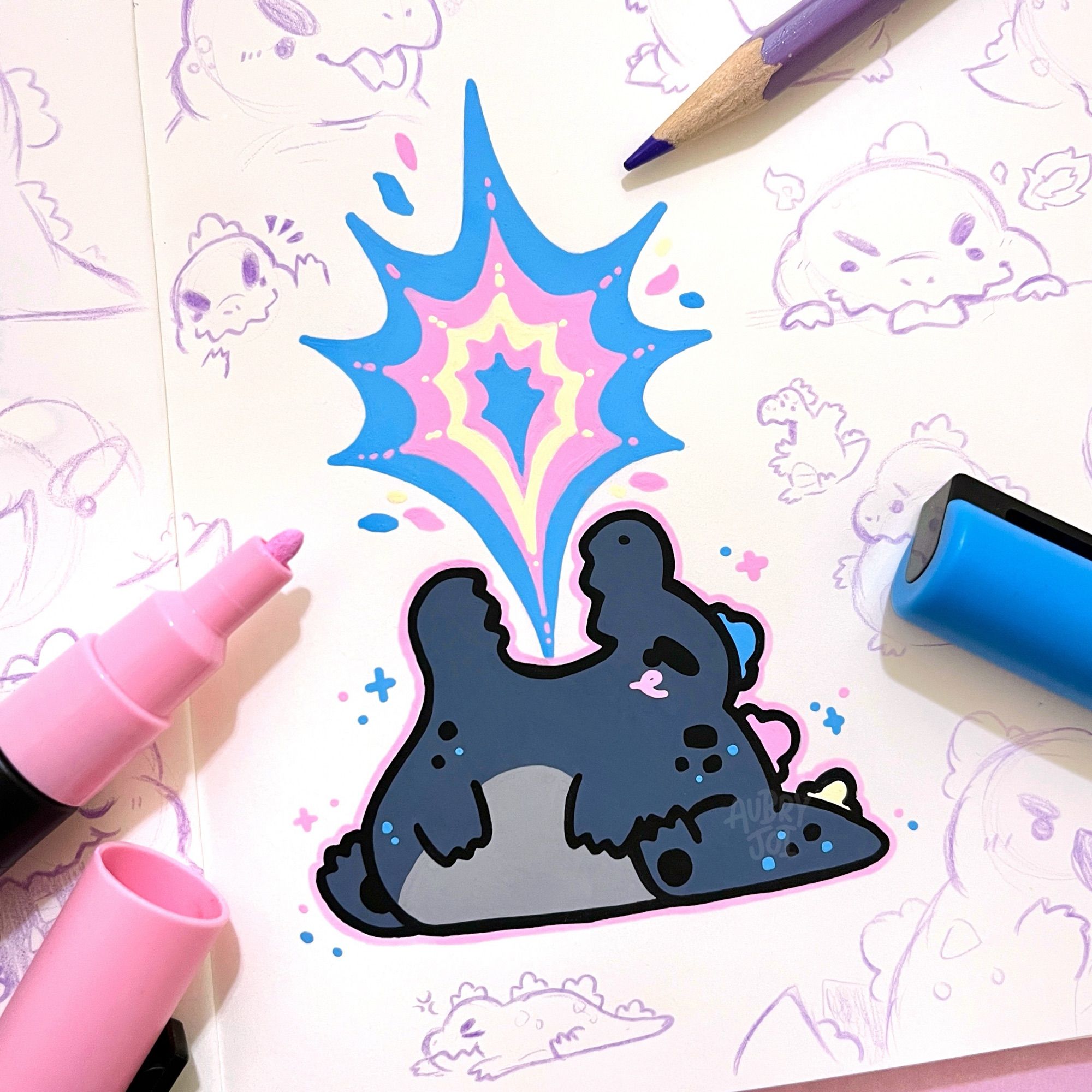 A drawing in a sketchbook of a kawaii-style, chubby Godzilla with his head tilted back and flames bursting from his open mouth. The flames are colored blue, pink & white like the trans flag. He has there spikes, each either blue, pink, or white. Around the drawing is various sketches of cute Godzilla done with pink pencil.