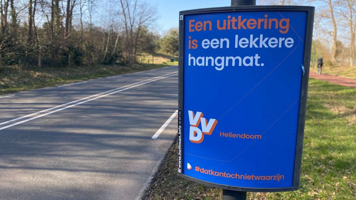 Reclamebord langs een weg. Op het bord staat: Een uitkering is een lekkere hangmat. 
VVD Hellendoorn. 
Onderaan het bord staat:
#DatKanTochNietWaarZijn