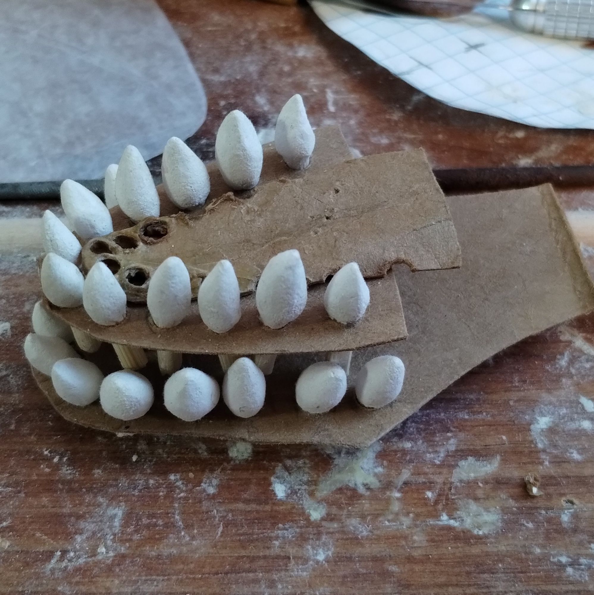 Two rows of teeth set in chipboard with a spare piece trimmed into a tongue shape