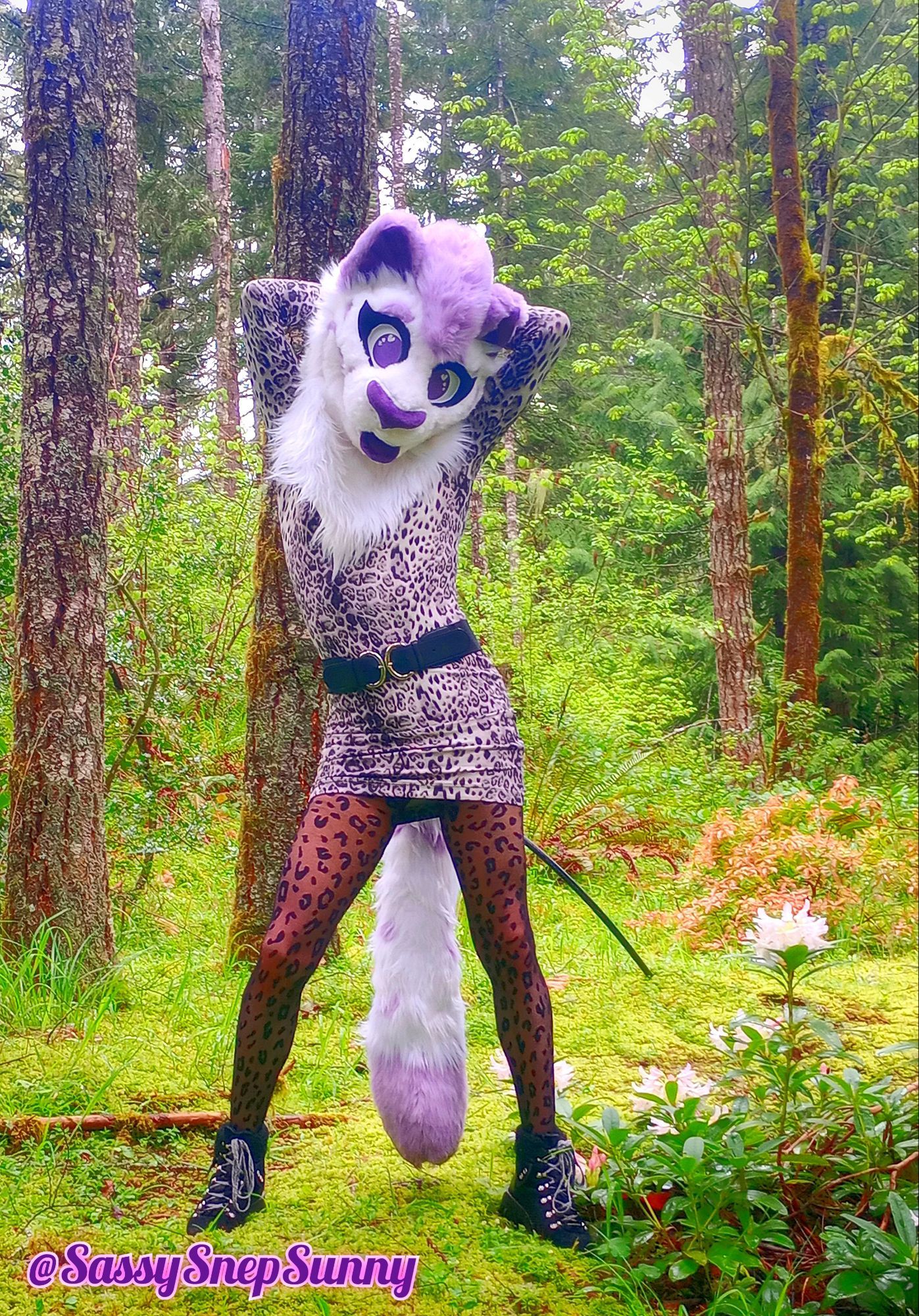 A purple spotted snep posing in the forest with her hands and arms behind her head, wearing a gray snep patterned dress and sheer black tights with rosettes