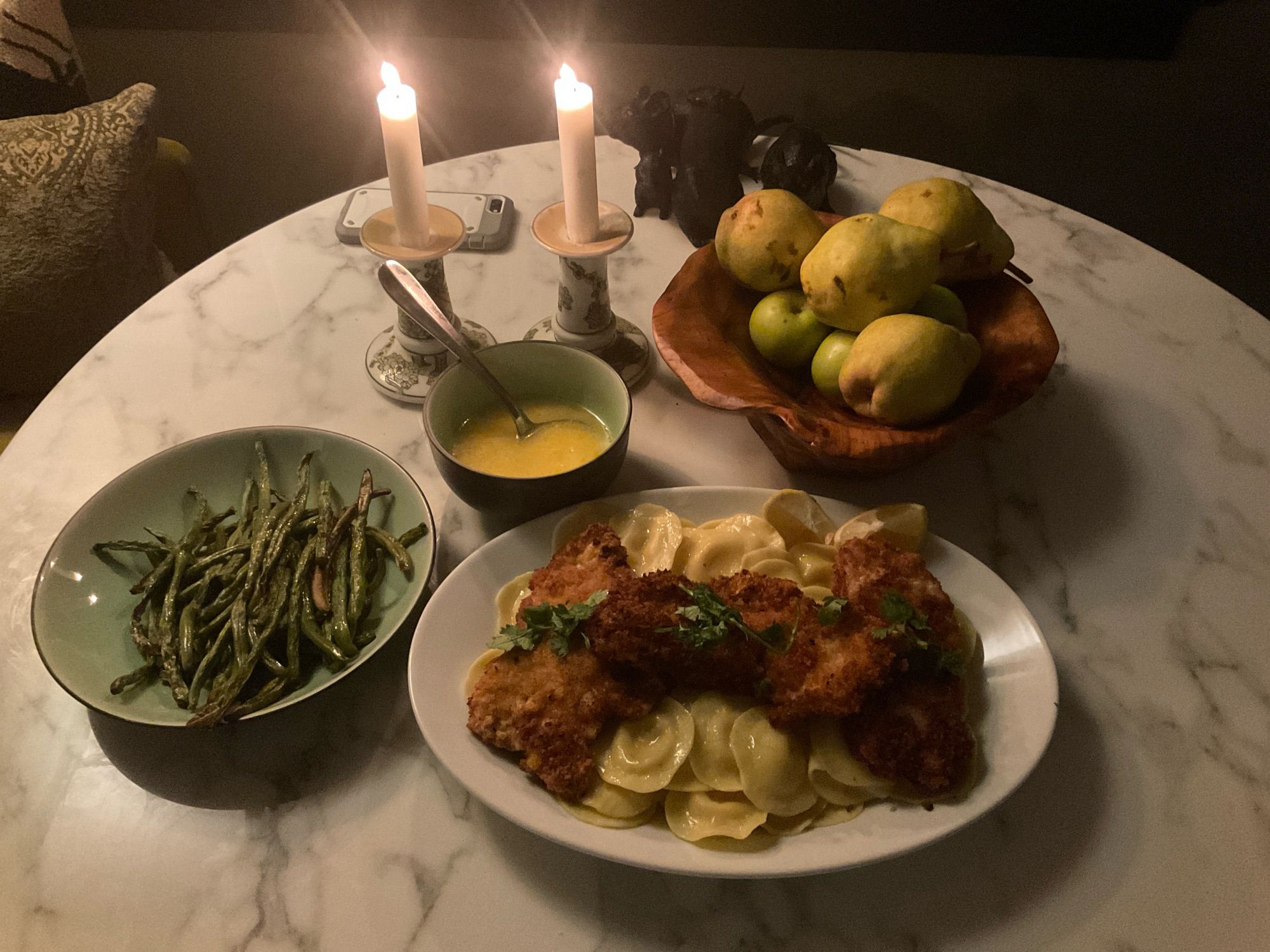 Schnitzel ravioli asparagus and some kind of sauce with some candles pears and a white table