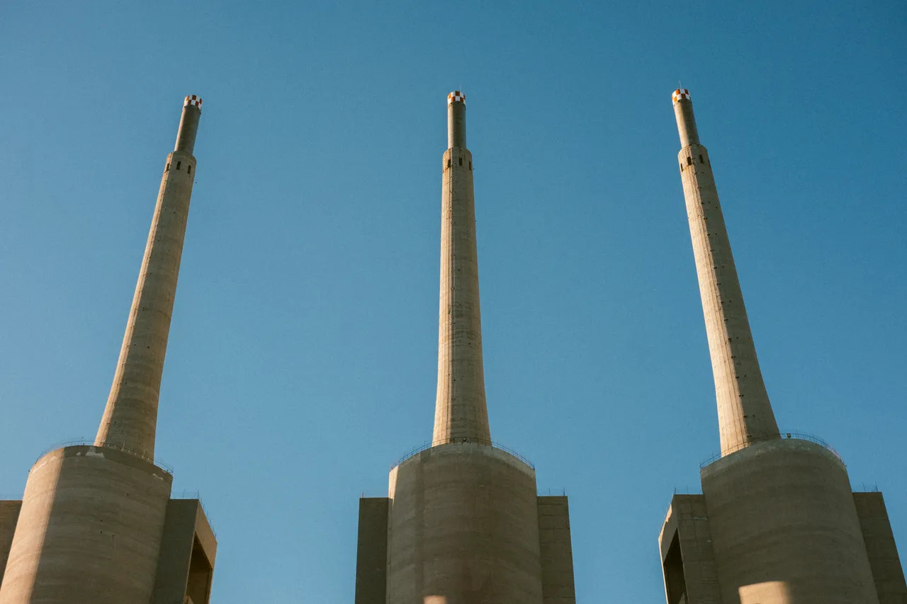 Three cylindrical chimneys under a clear blue sky.