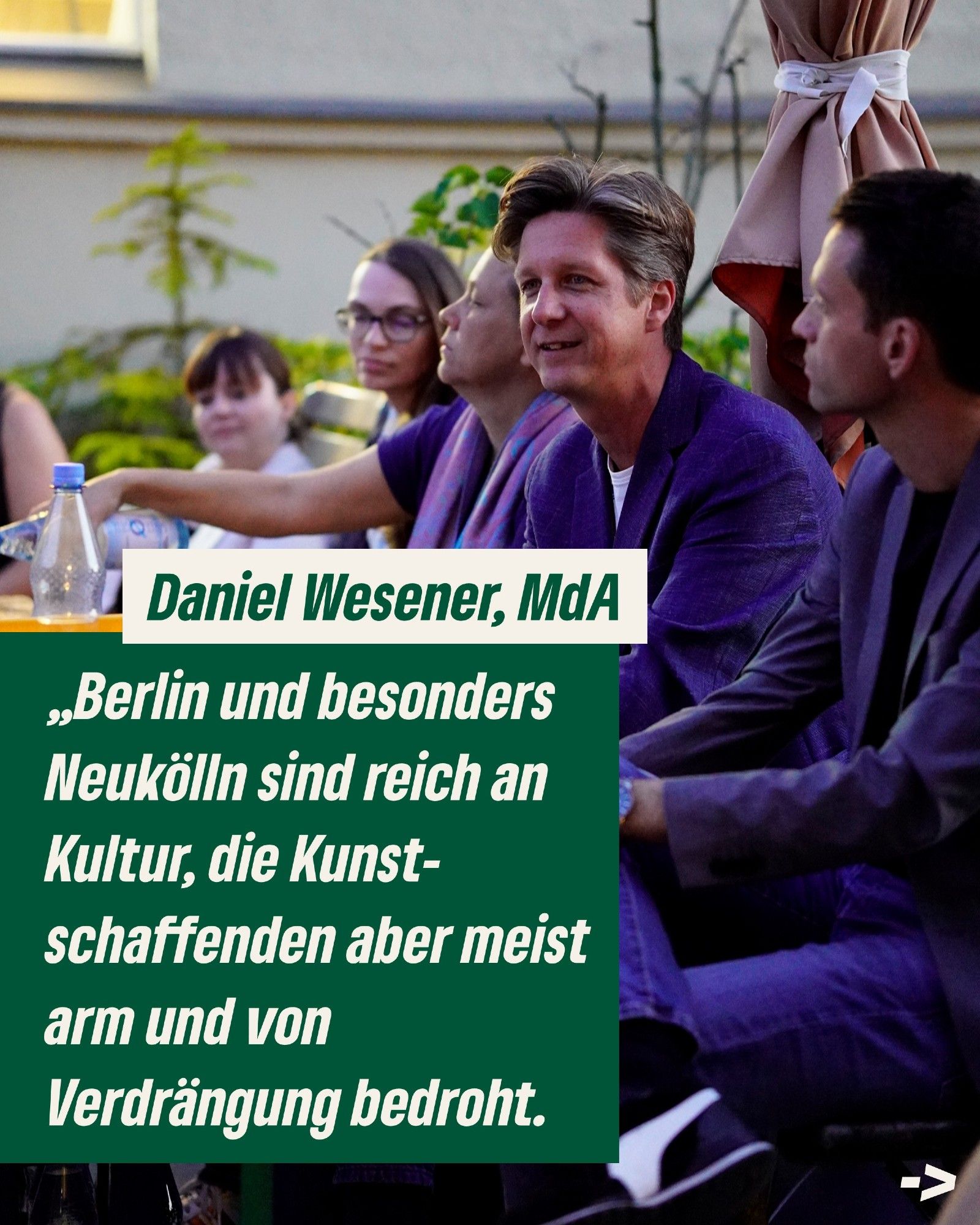 Das Bild zeigt Menschen auf einer Bank auf der Dachterrasse der Neuköllner Oper. Einer von ihnen spricht. Unten steht als Zitat von Daniel Wesener der Text: "Berlin und besonders Neukölln sind reich an Kultur, die Kunstschaffenden aber meist arm und von Verdrängung bedroht."