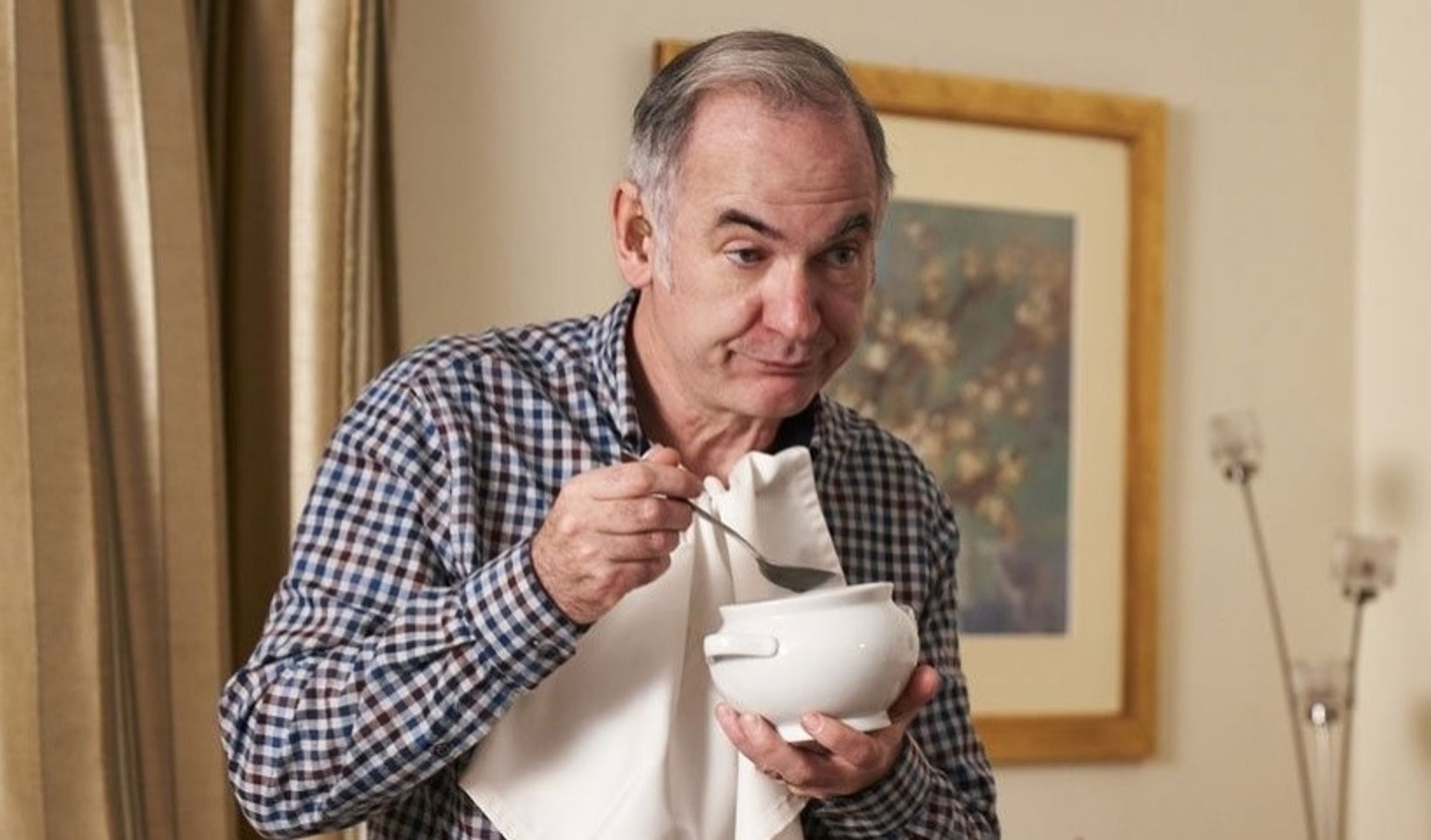 Martin from Friday Night Dinner, a middle aged white man eating out of a soup bowl