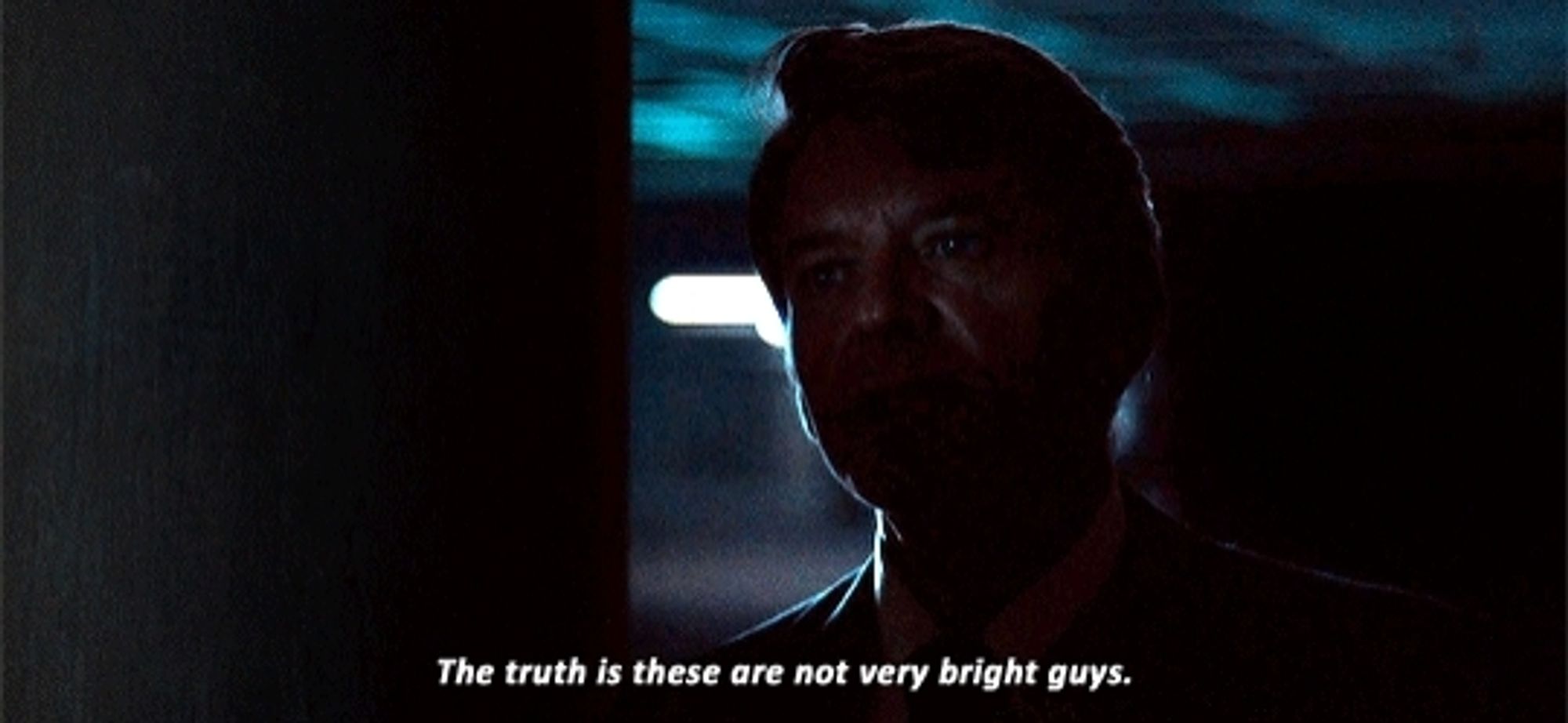 A man stands in the shadows in a parking garage. Caption reads "The truth is these are not very bright guys"