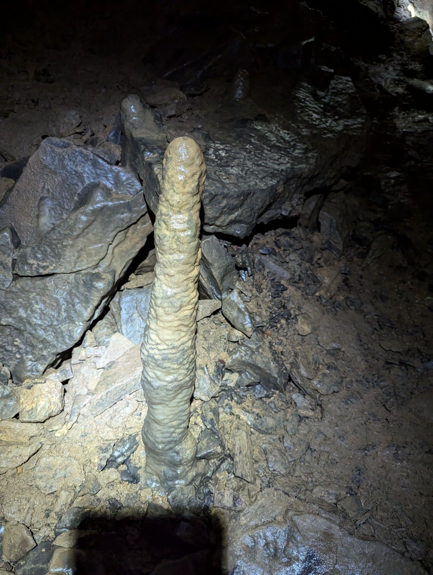 Phallic stalagmite with rock rubble behind it.