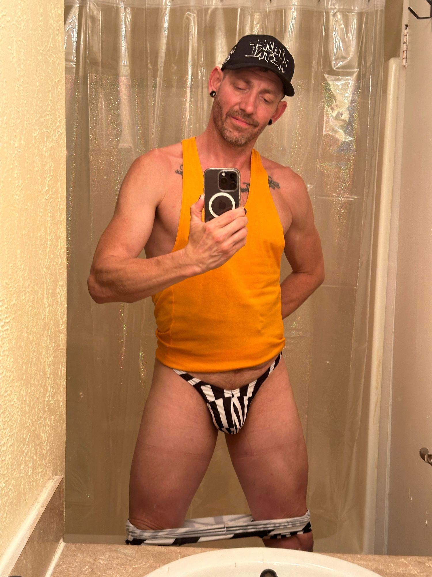 Bathroom selfie of me. Wearing black and white graphic thong and an orange stringer tank.