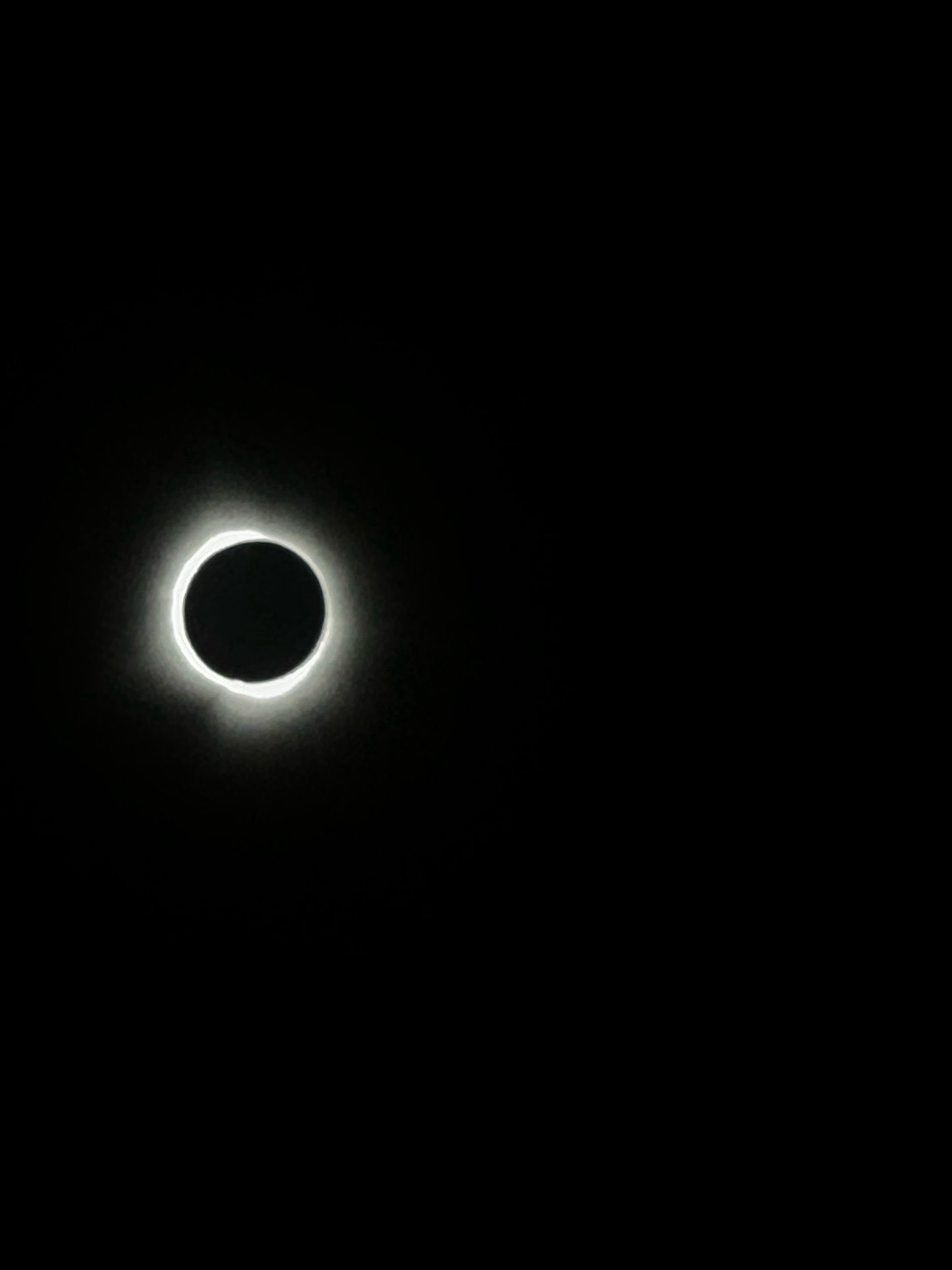 A picture of the sun during a total solar eclipse, it shows as a glowing white ring around a black circle, on a totally black background.