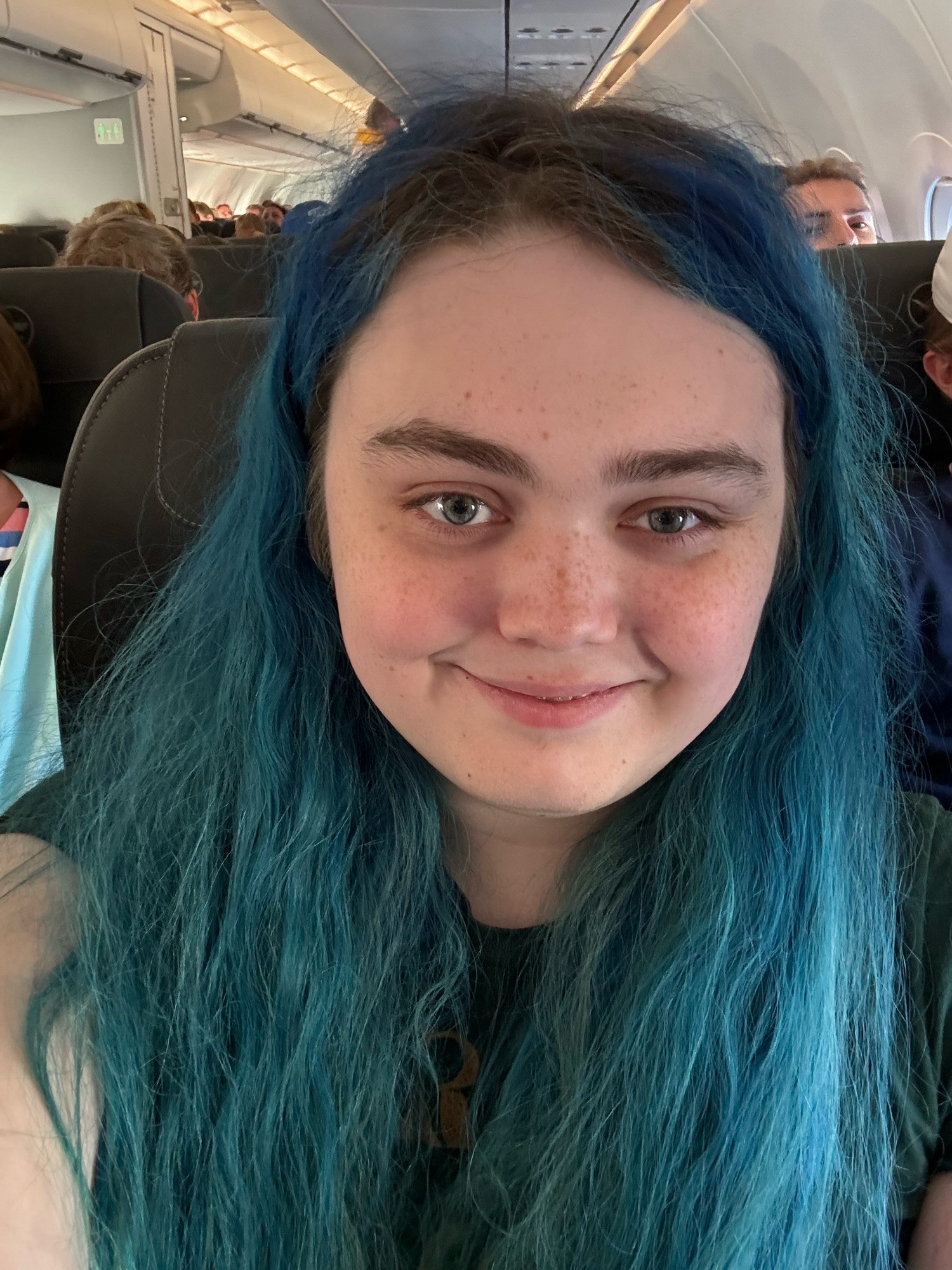 me sitting in an Airbus A321neo (specifically, seat 20B, a middle seat on the left side). I’m smiling and my hair covers my shirt making it impossible to make out