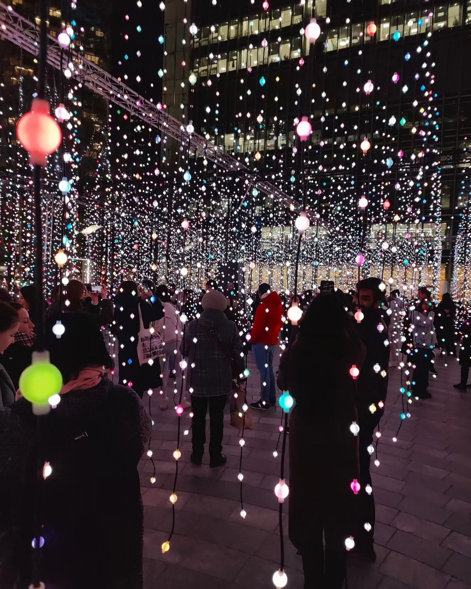 People standing amongst strings of coloured lights