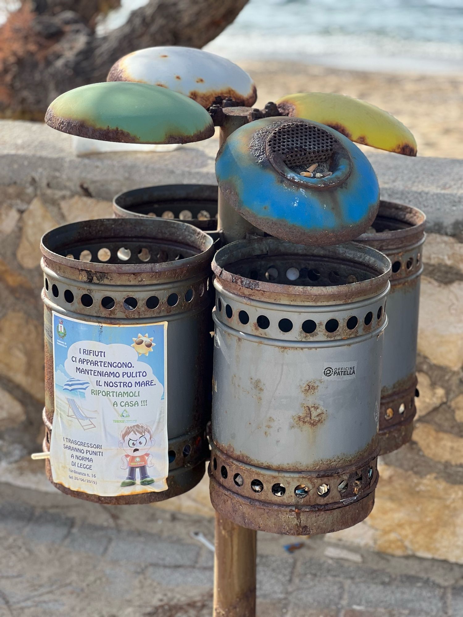 Rubbish bins on the beach. Cylindrical with colourful covers for recycling. All very rusty and, ahem, trashed.