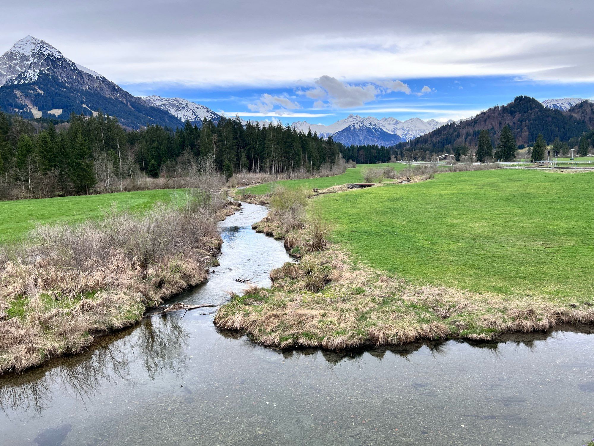 Brook, meadow, mountains. High alps in spring, with snow on top.