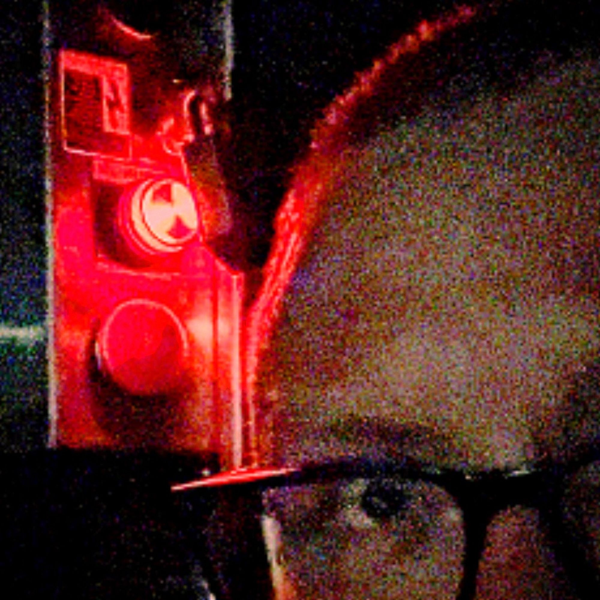 a grainy picture of lintile’s face, in front of a red button, with a red status light above it. you know they’re thinking of pushing it