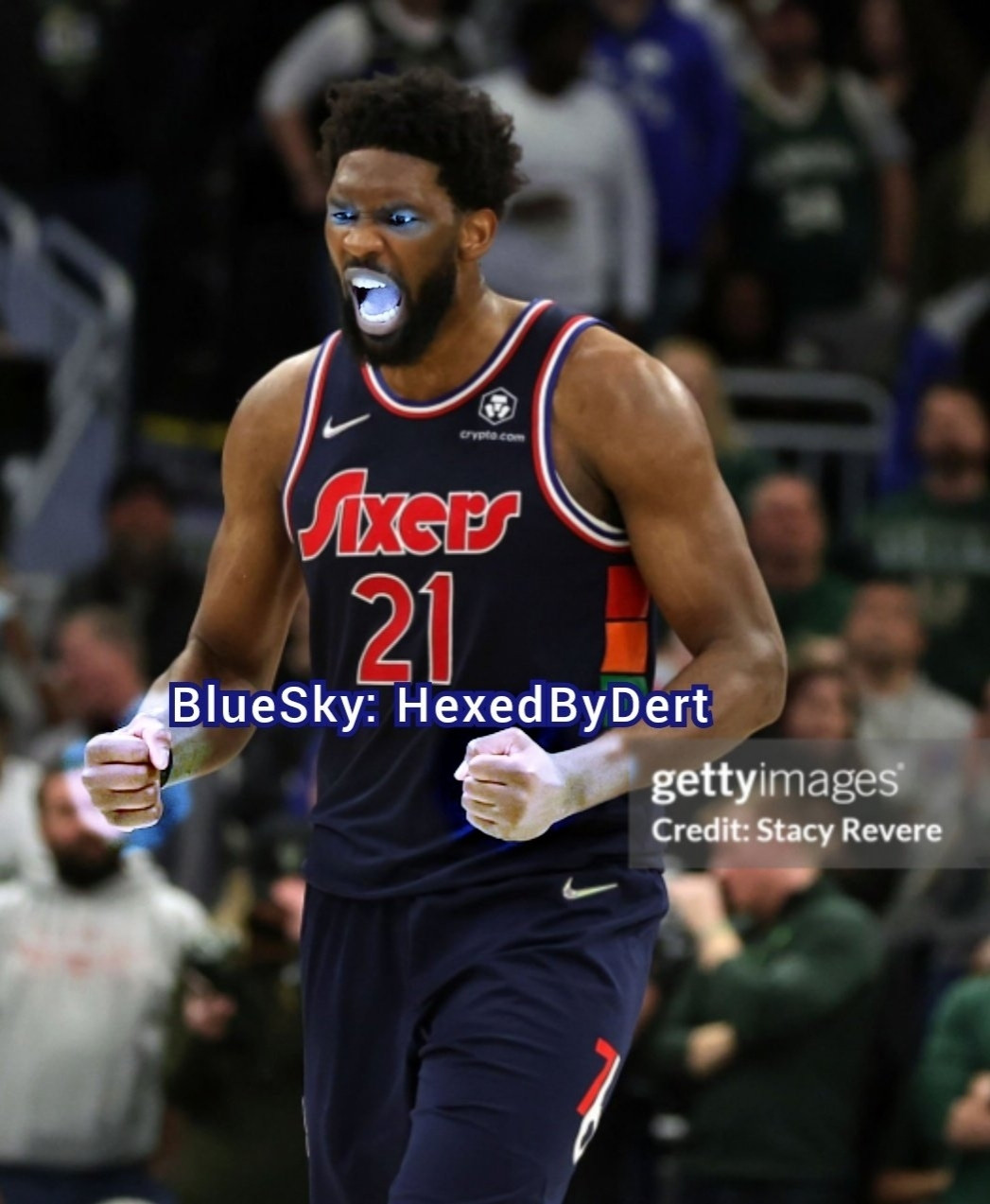 Joel Embiid screams during a game na sixers 21 jersey. His eyes and mouth light up blue. His hands are clenched into fists and edited like ice.
Getty images. Credit. Stacy Revere