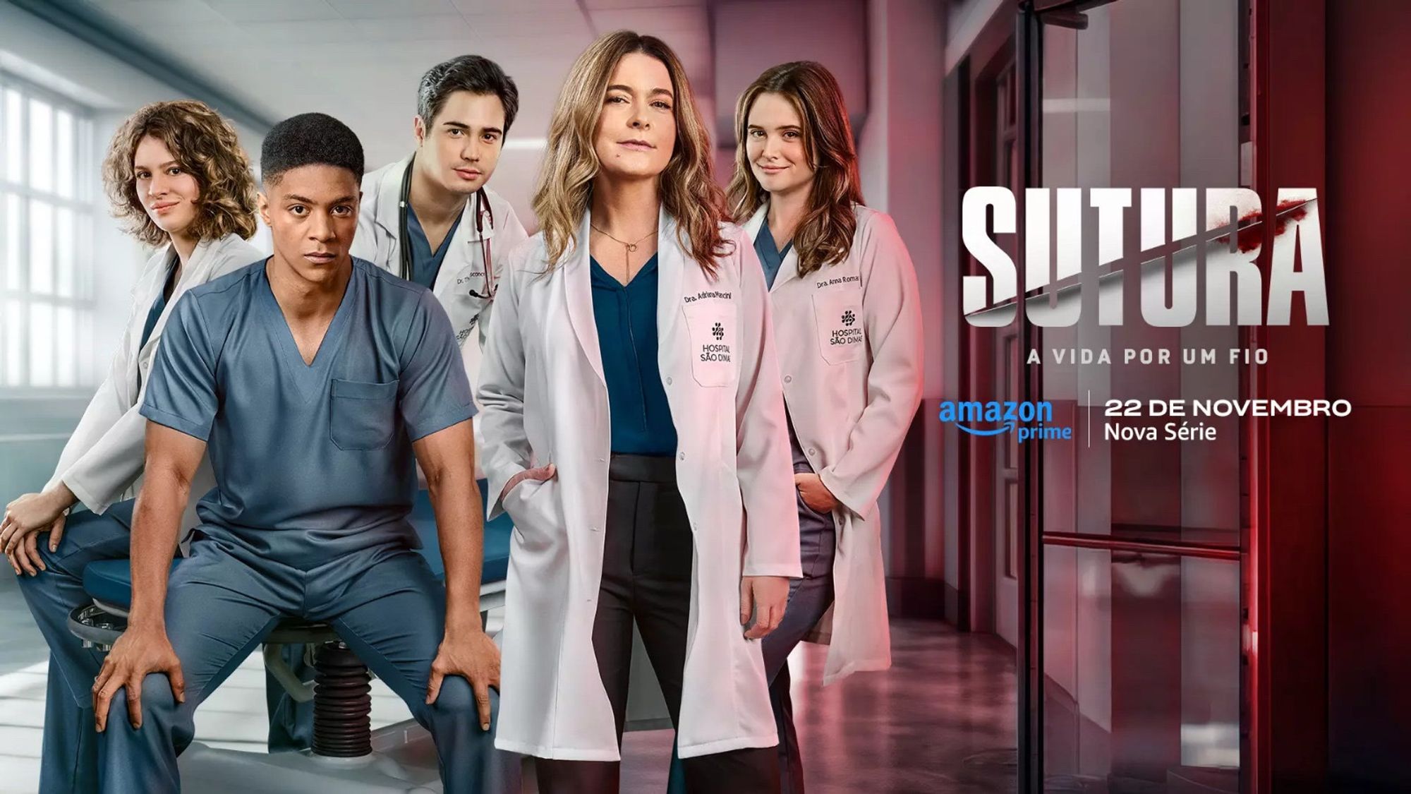 A imagem mostra a capa promocional de uma série médica chamada "Sutura", com o subtítulo "A vida por um fio", que será lançada no Amazon Prime em 22 de novembro. No centro da imagem, cinco personagens em trajes médicos estão posicionados em um hospital, com destaque para uma mulher mais velha no meio, cercada por médicos mais jovens. Eles usam jalecos brancos e azuis, com expressões sérias. Ao fundo, um corredor hospitalar com iluminação suave e predominância de cores em tons de azul e vermelho.