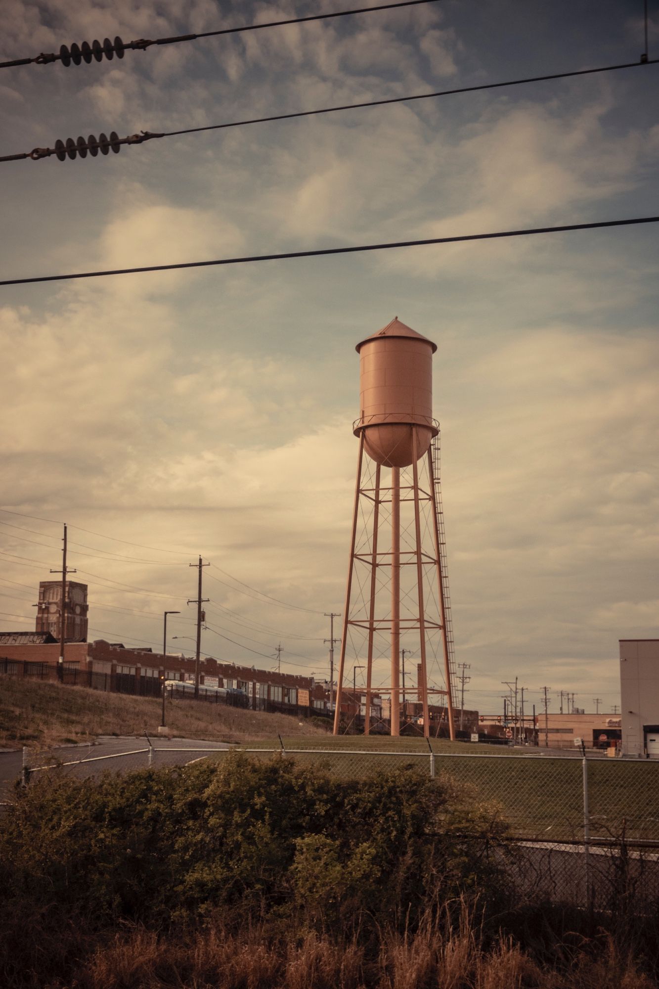 a metal water tower in the late afternoon sun as seen from the train