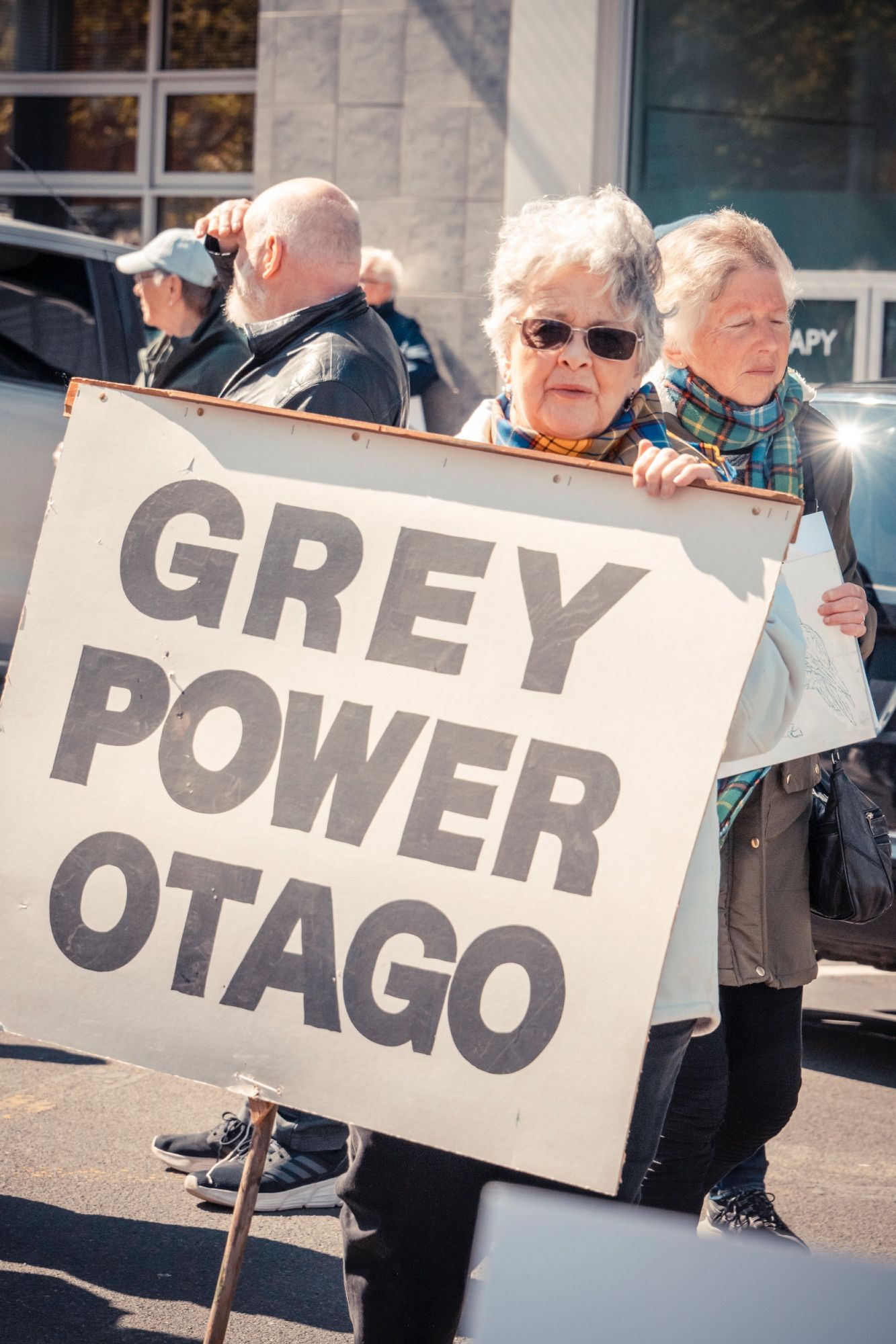 A woman holding Grey Power Otago sign