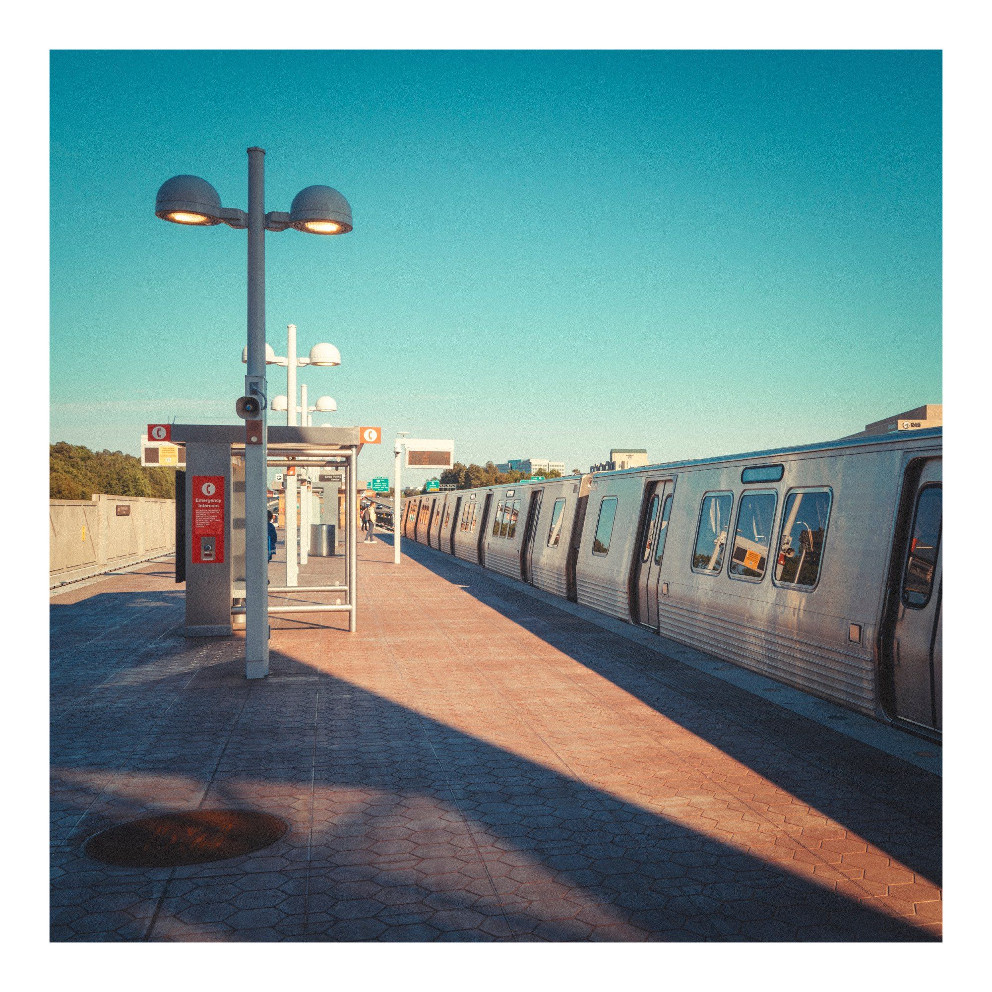 a train station at Dulles airport Washington, the metro train taking me back to Washington.  Blue skies, silver stationary train & largely deserted platform. Early evening muted tones