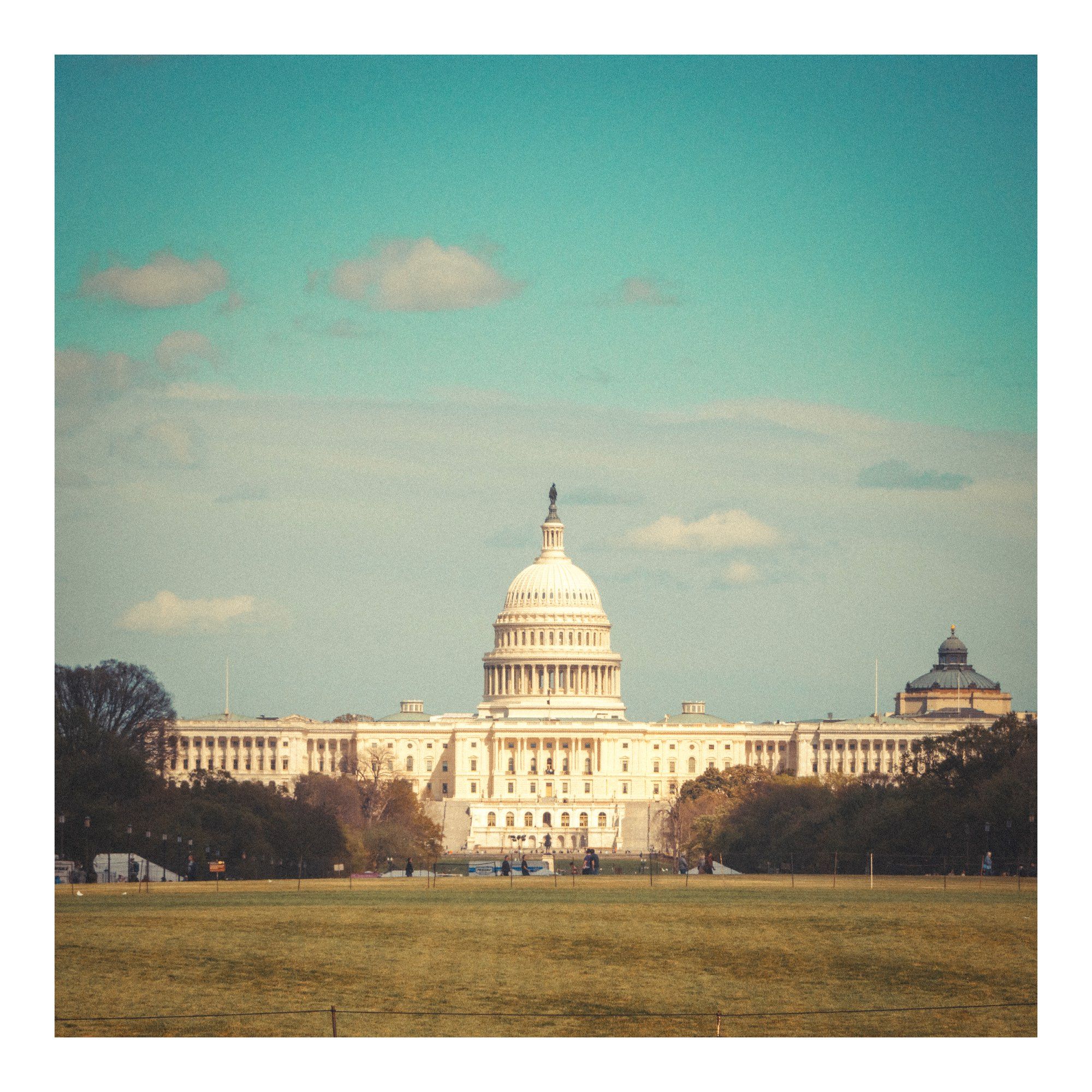 A view down the National Mall to the US Capitol Building & it's magnificent dome.

Old grainy film style image.  Green grass in foreground, white classical styled building, with partly cloudy sky