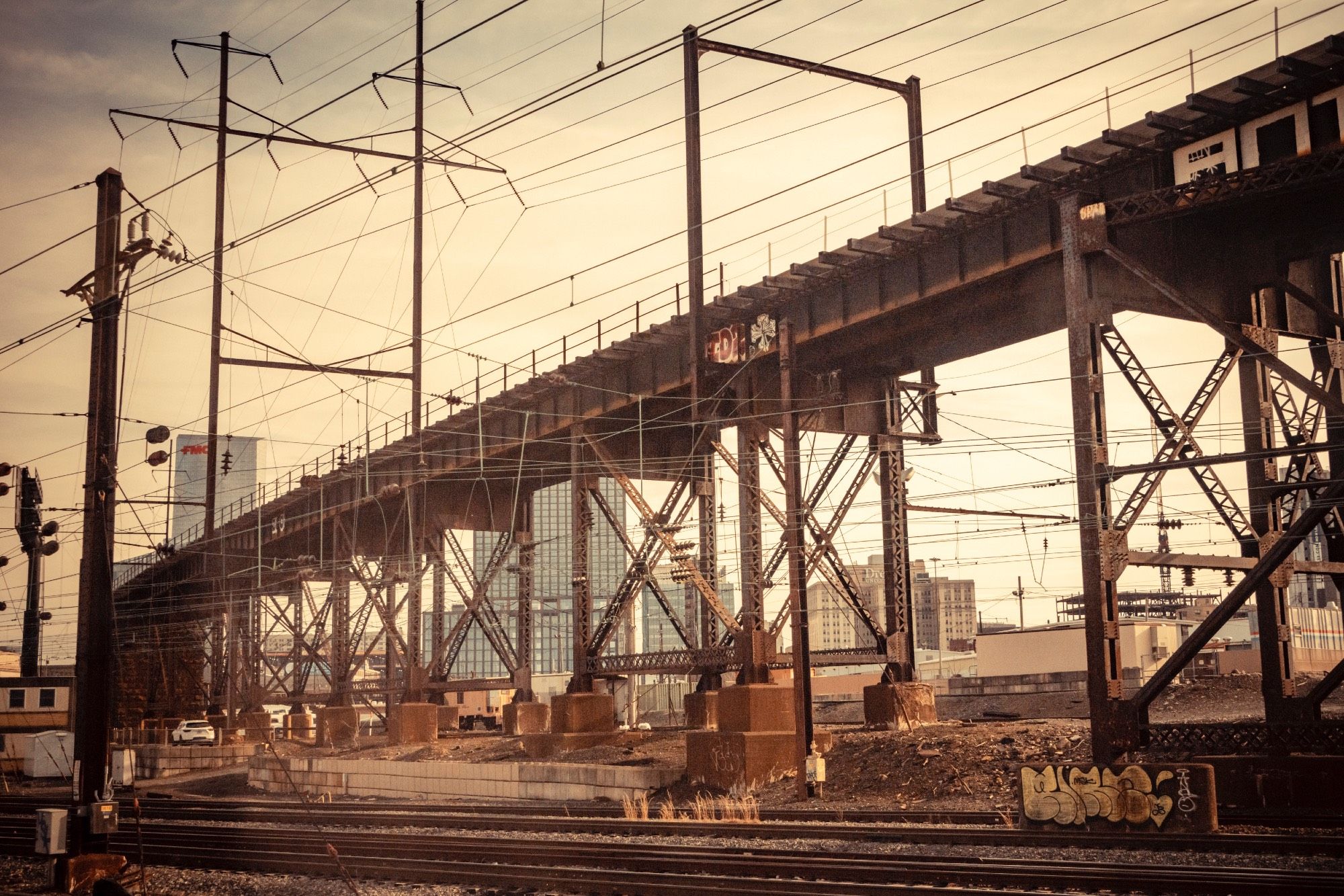 industrial wasteland of iron, power cables with a bridge, with a city in the back ground. Warm early evening summer tones