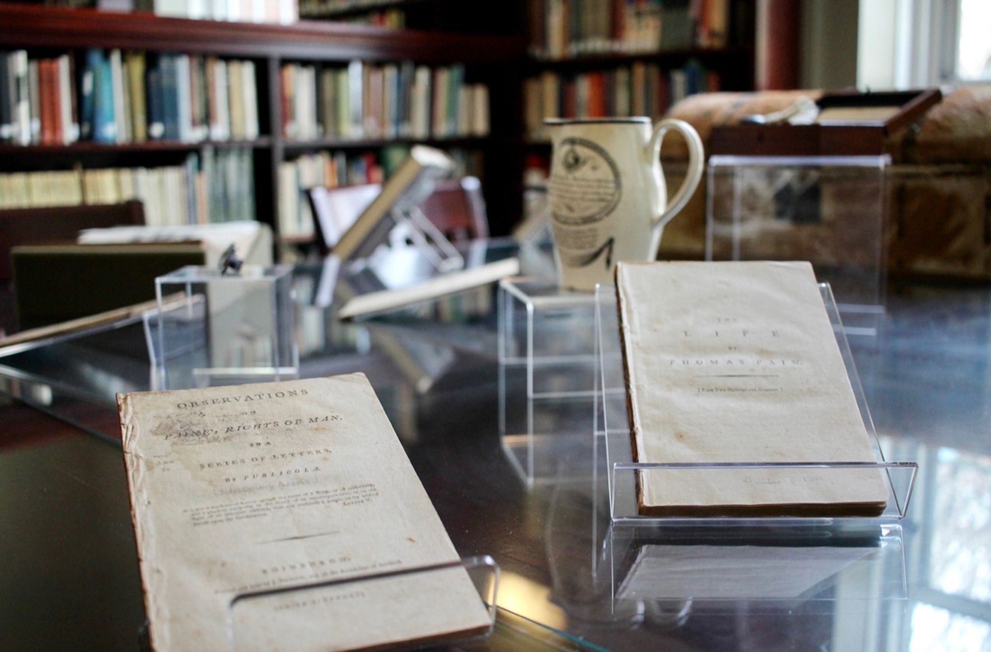 A series of pamphlets on a brown table in front of a colorful wooden bookshelf