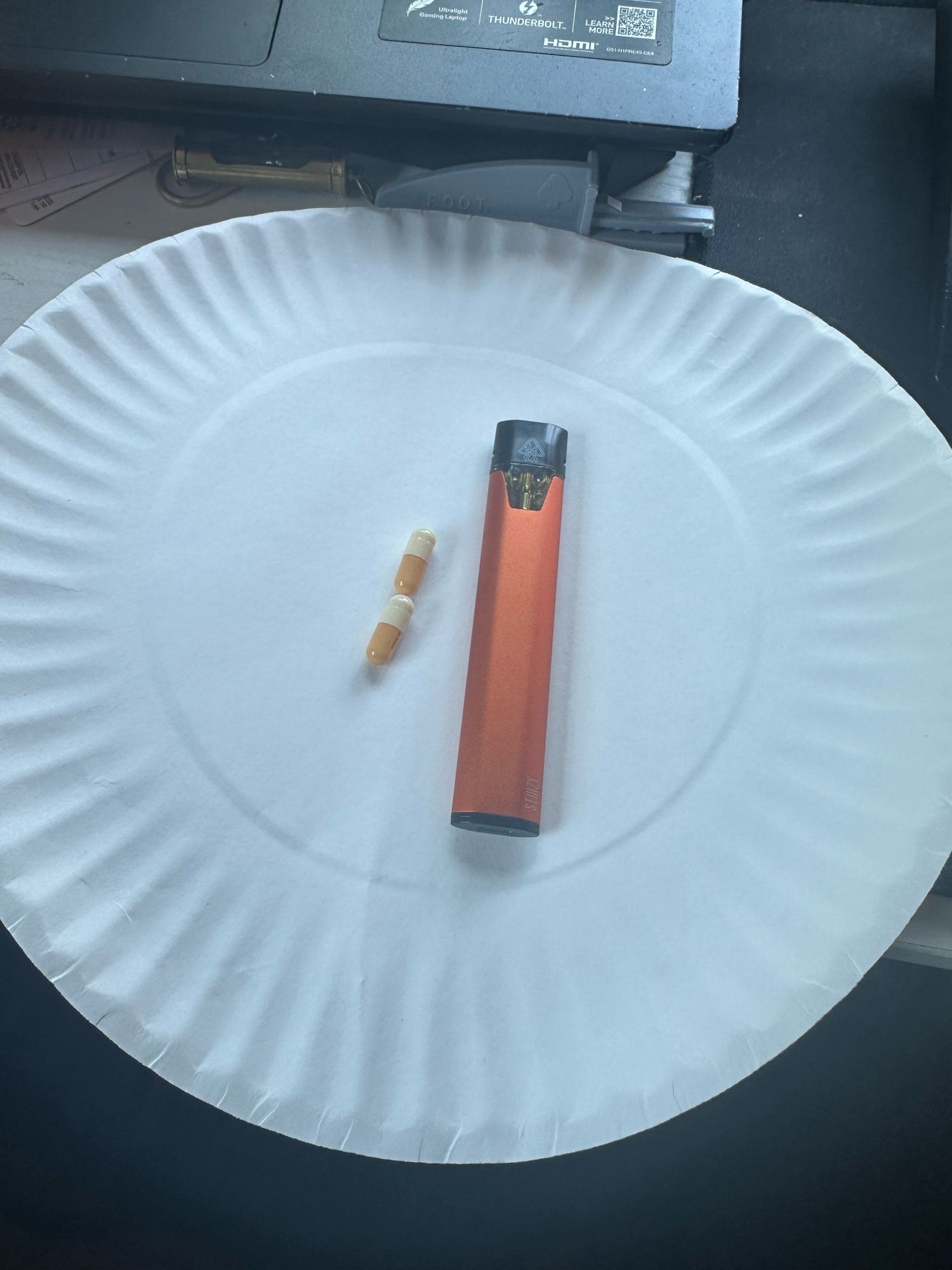 a paper plate with a stizzy and 2 capsules of adderall