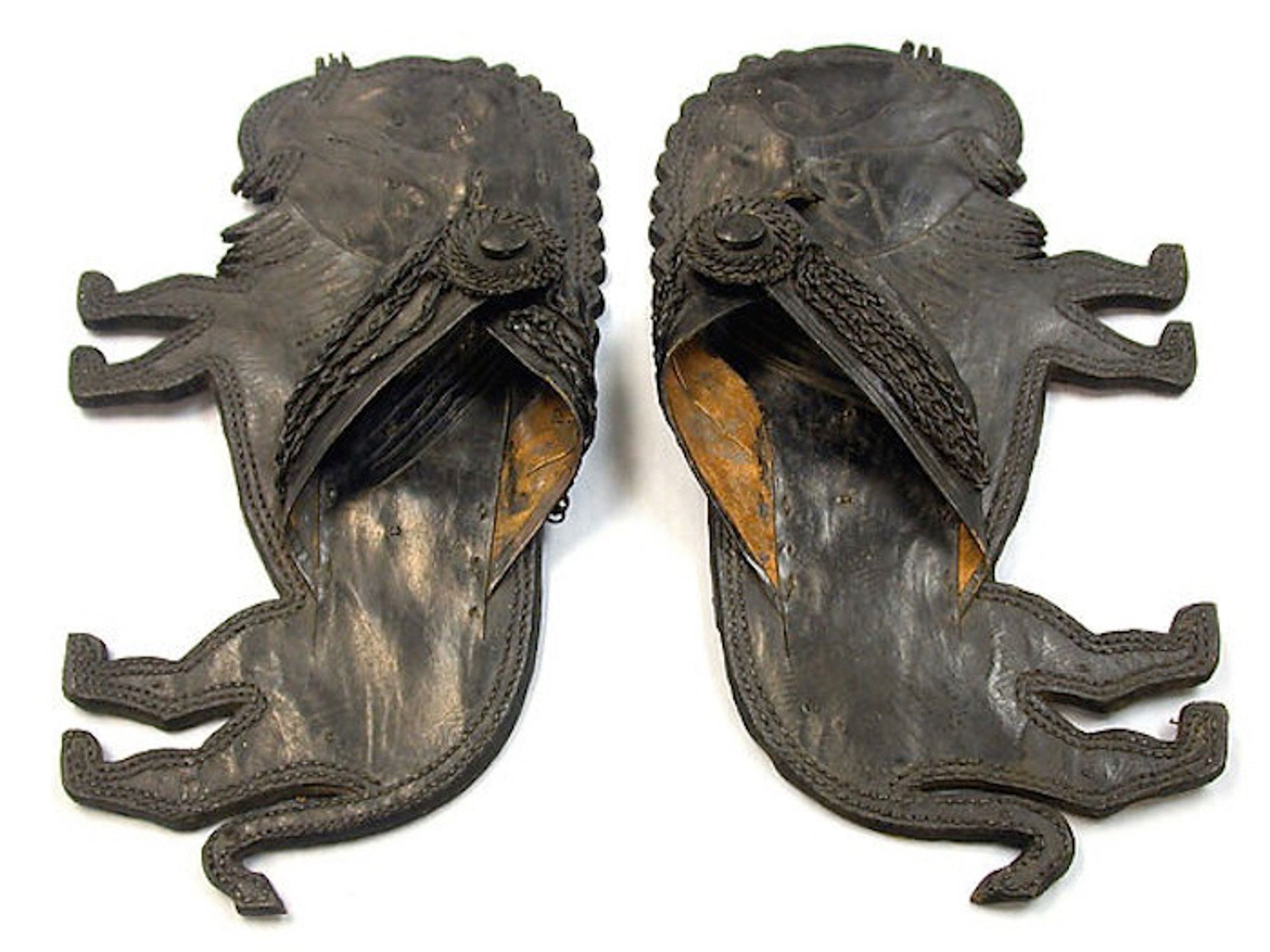 official museum photo, top down view on white background: pair of sandals each in the form of maned male lions in standing side profile, dark brown leather