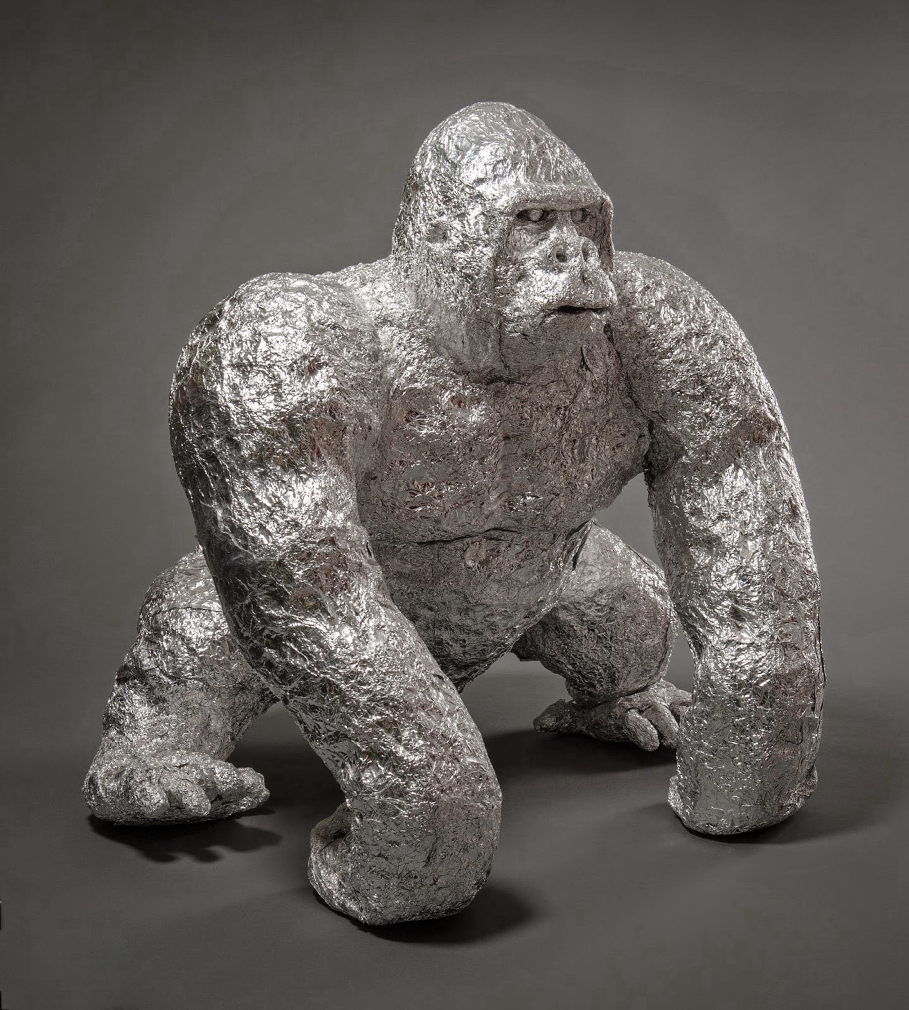 official museum photo of the object on grey background: large aluminum foil sculpture of a gorilla