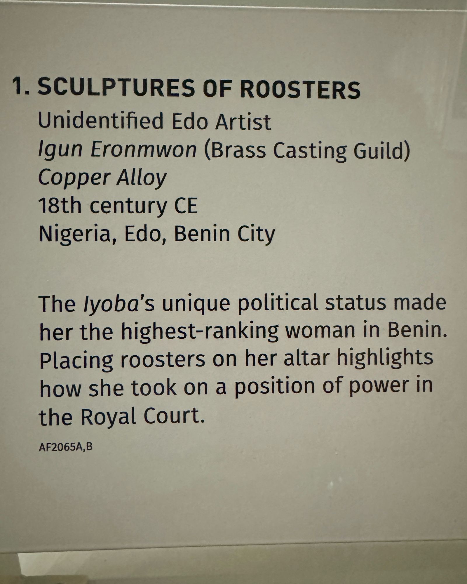 gallery label:
“1. SCULPTURES OF ROOSTERS
Unidentified Edo Artist
Igun Eronmwon (Brass Casting Guild)
Copper Alloy
18th century CE
Nigeria, Edo, Benin City
The lyoba's unique political status made her the highest-ranking woman in Benin.
Placing roosters on her altar highlights how she took on a position of power in the Royal Court.
AF2065A,B”