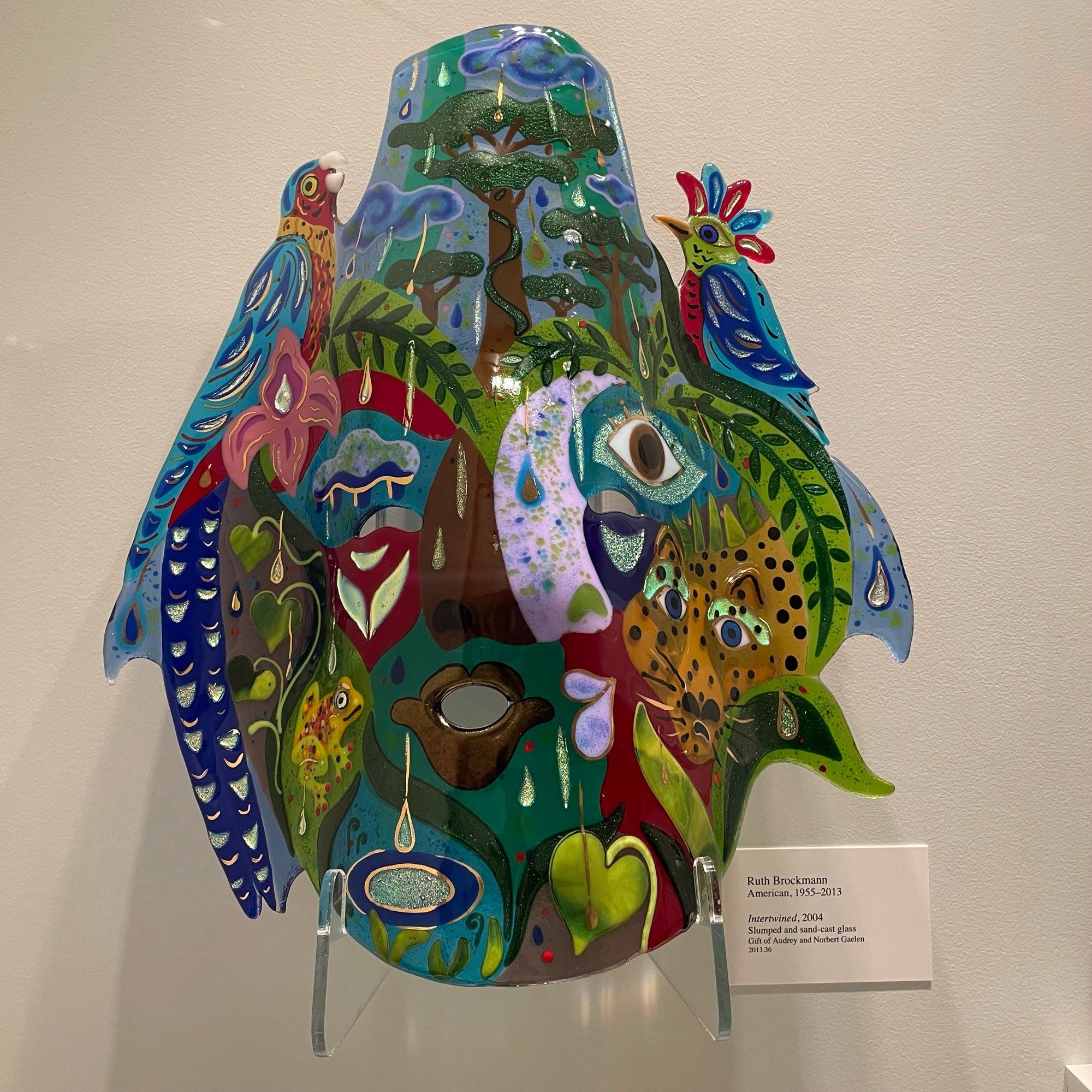 photo of art glass piece on display at museum: rainforest flora and fauna collage design