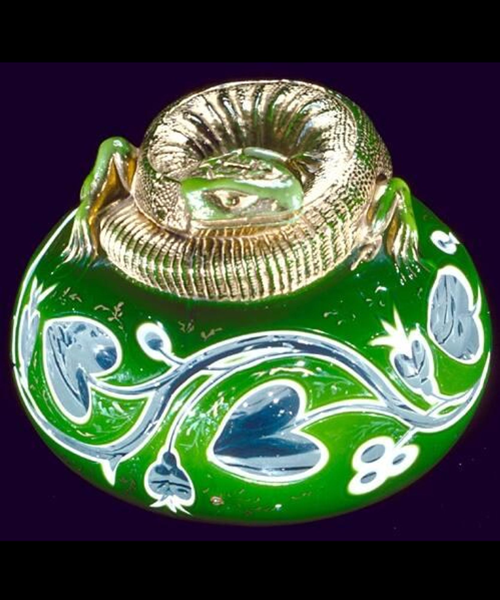 official museum photo of lizard paperweight #2 on black background: lime green glass with blue and white ornamentation, topped with curled up silver lizard
H 6.5 cm, Diam 8.5 cm