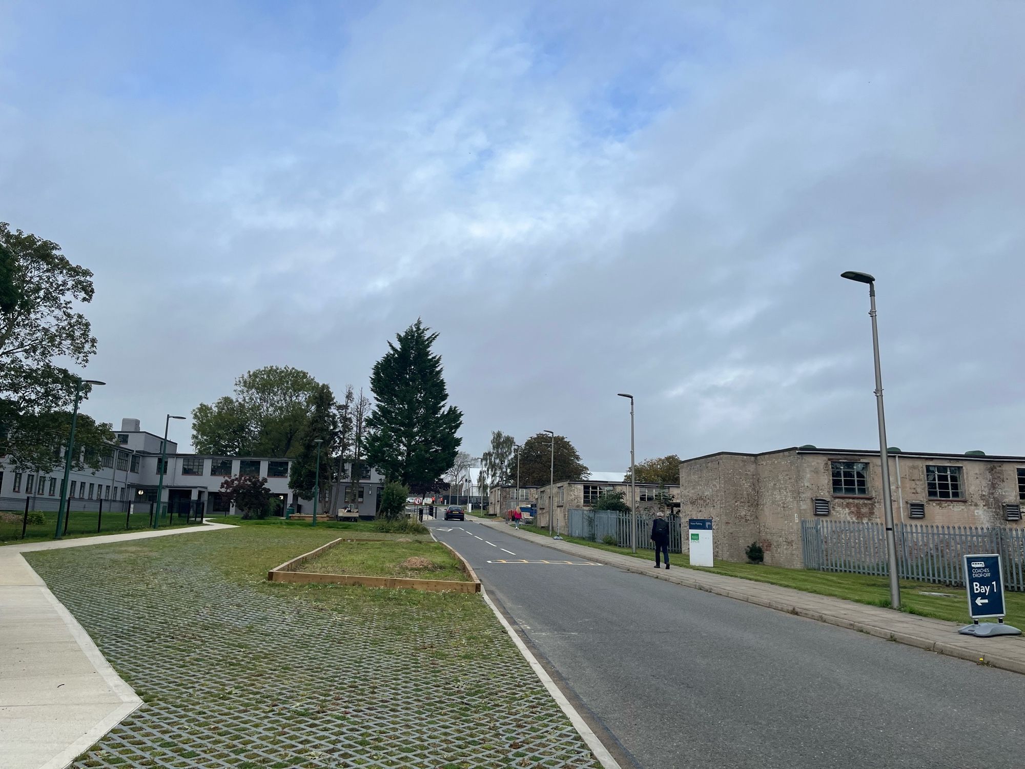 Photo of Bletchley Park, refurbished grey huts to the left, brick huts in a poor condition on the right