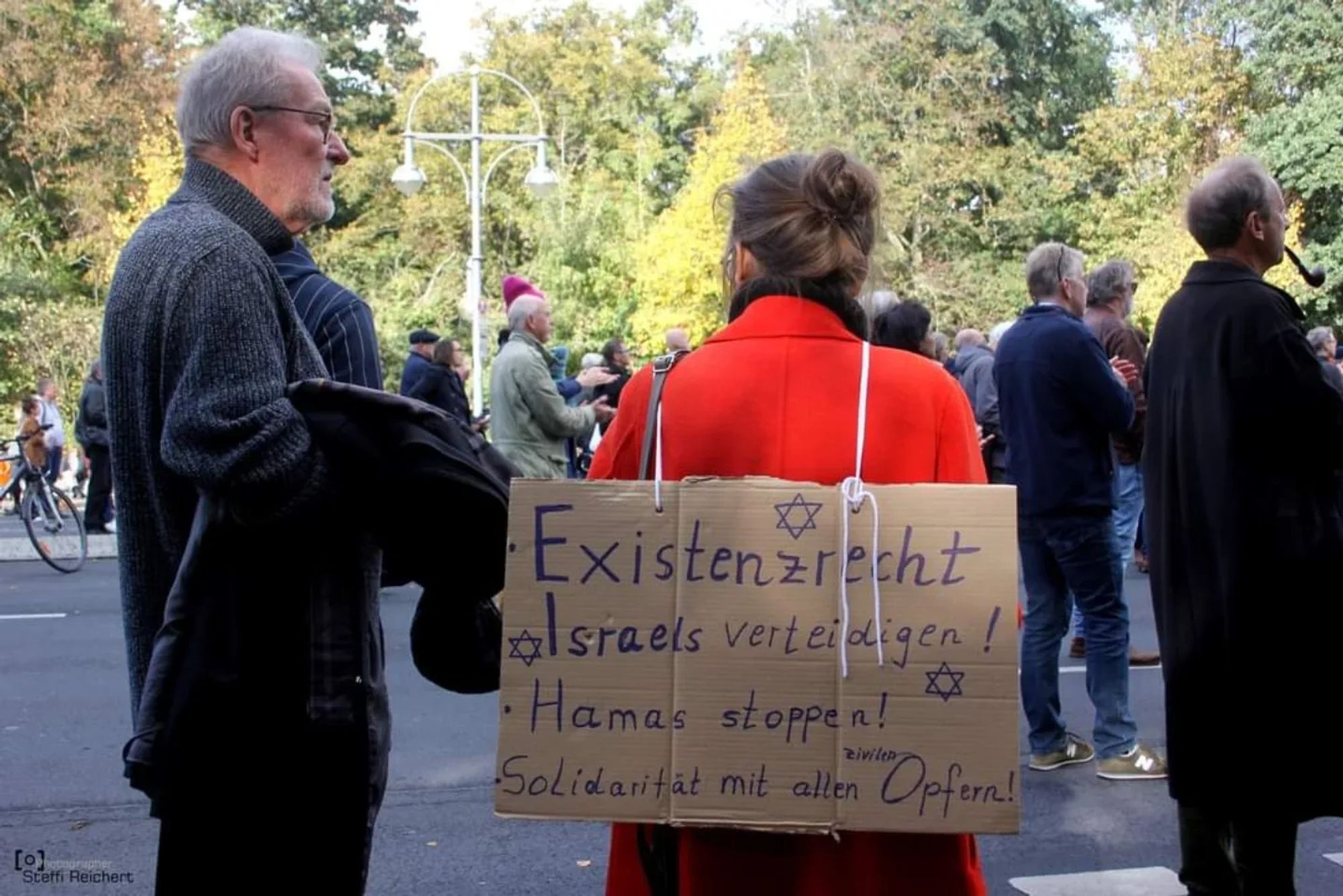 Menschen vor dem Brandenburger Tor mit Plakat, auf dem steht: "Existenzrecht Israels verteidigen! Hamas stoppen! Solidarität mit allen zivilen Opfern!".