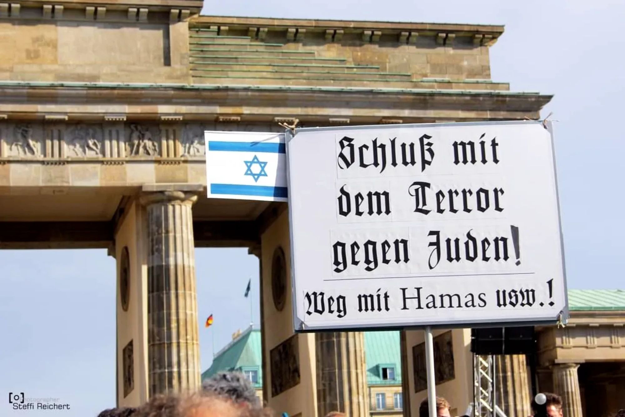 Menschen vor dem Brandenburger Tor mit Plakat, auf dem steht: "Schluss mit dem Terror gegen Juden! Weg mit Hamas usw.".