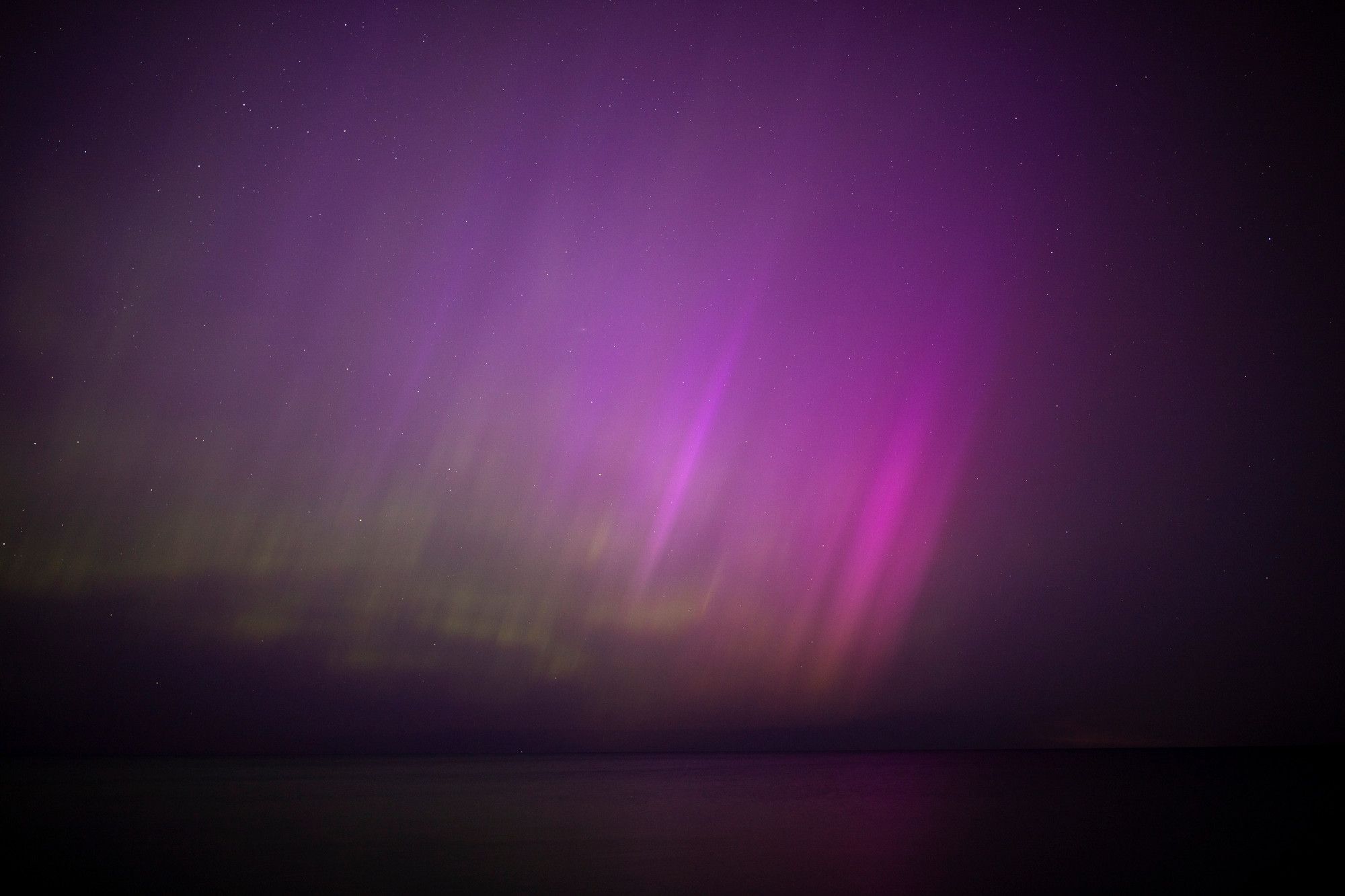 Looking out over Lake Michigan with Chicago's light pollution at my back it didn't matter whatsoever - bright green waves and purple spikes of aurora shining bright enough to reflect off the calm waters, entirely filling the majority of the frame, darkening at the edges into a natural vignette