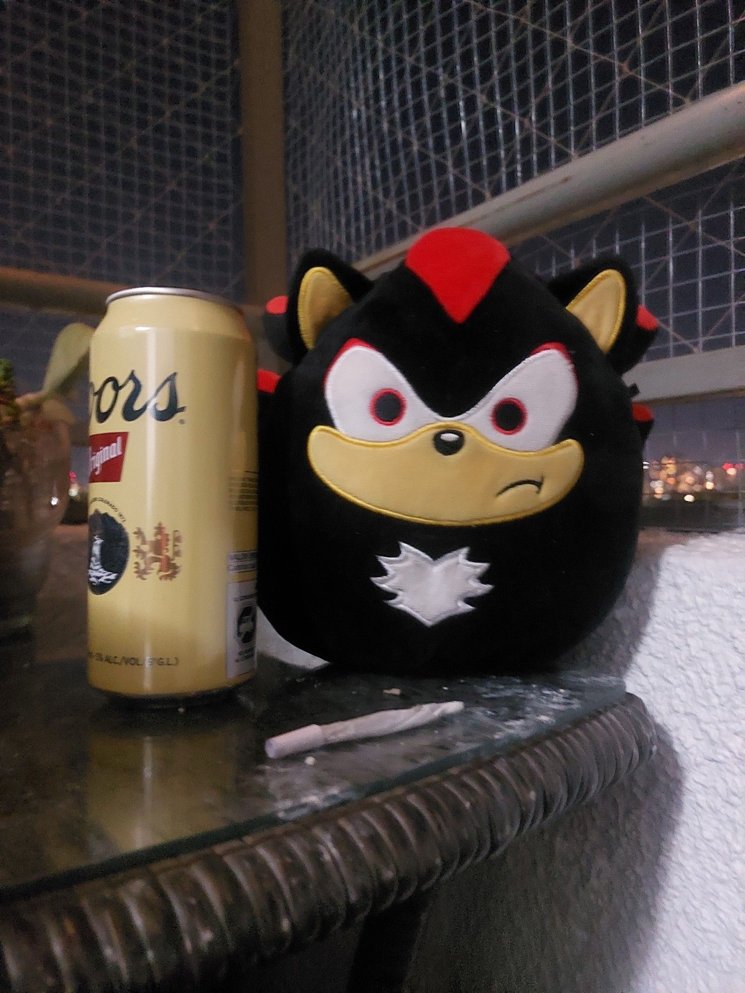 Table with a joint, a coors beer, and a shadow the hedgehog squishmallow, near midnight