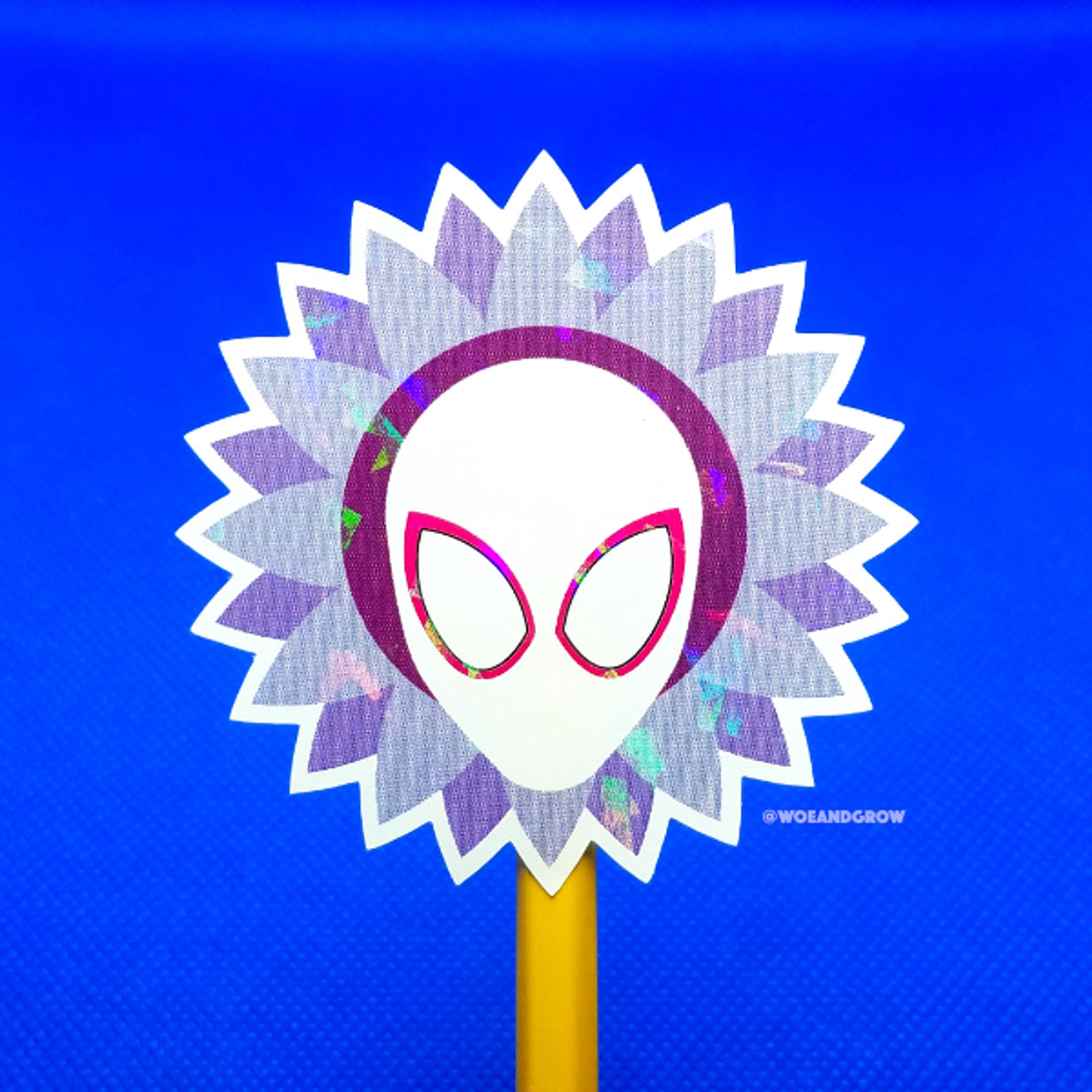 Photo of my Spiderverse Sunflower holographic sticker held up on a pencil