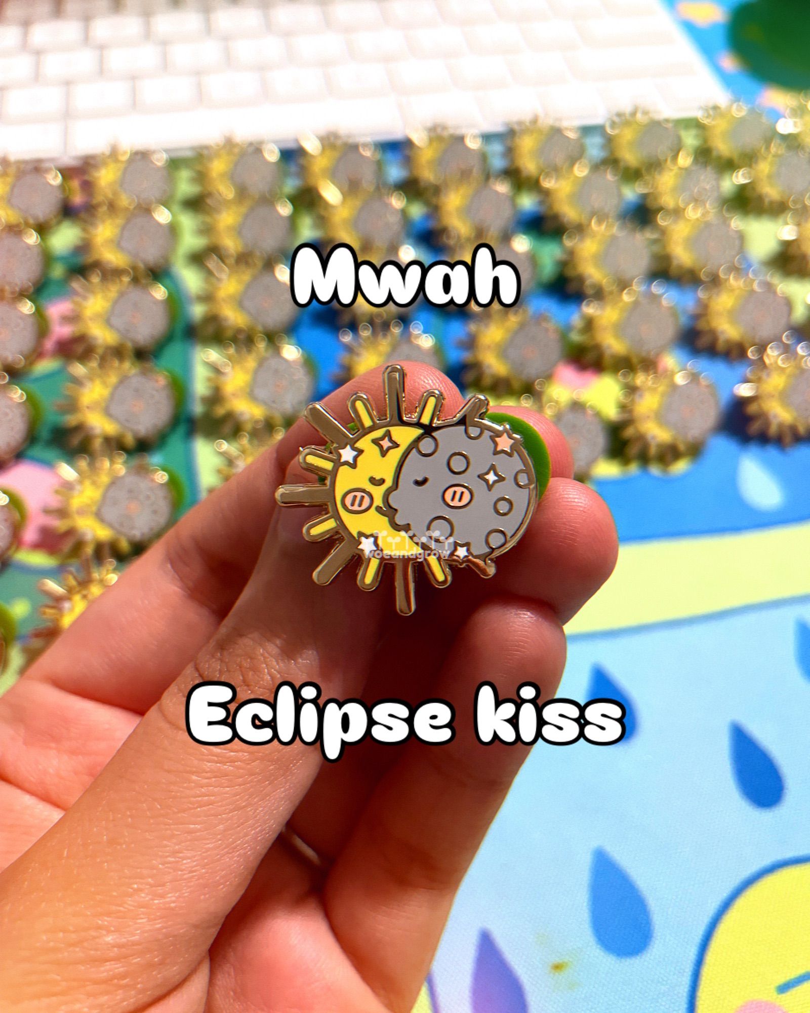 A closeup photo of my Eclipse Love enamel pin in hand with the text “Mwah” and “Eclipse kiss” overtop the photo