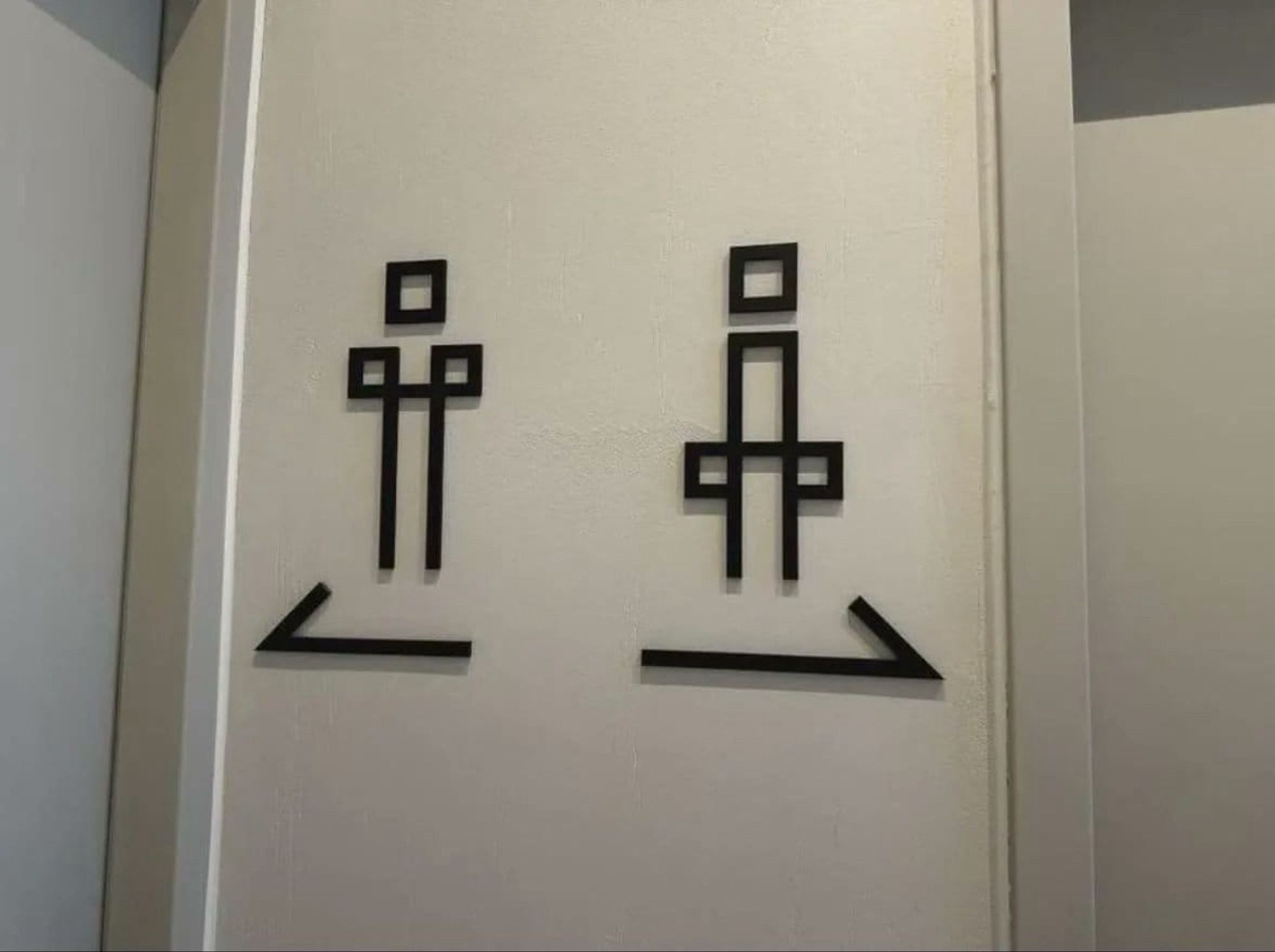 Deux signes indiquant des toilettes mais tellement mal foutus qu'il est difficile de dire quel coté est pour les homme et lequel pour les femmes.