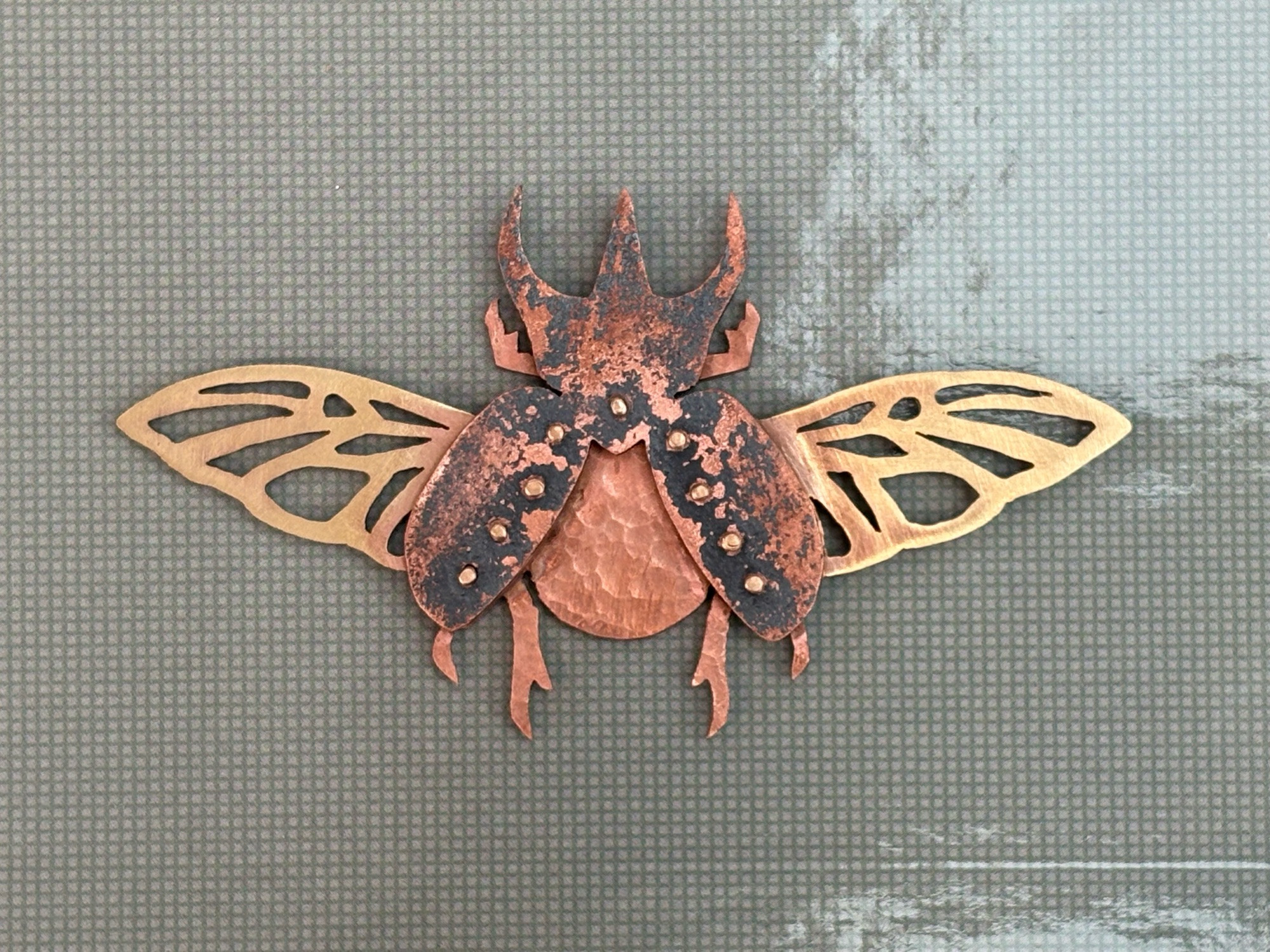 A beetle made of three sheets of metal (copper and brass) riveted together.