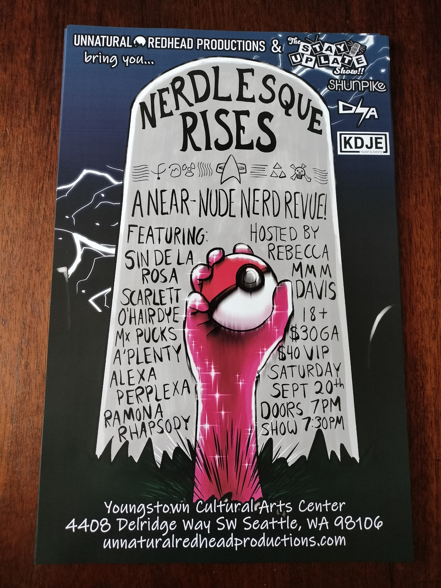 A photo of a stack of printed 11x17 posters featuring an illustration of a tombstone on a dark night with a hand clad in a sparkly pink glove shoving up out of the dirt, holding a Pokeball. Text reads:
Unnatural Redhead Productions and the Stay Up Late Show bring you...
NERDLESQUE RISES
A near-nude nerd revue!
Featuring:
Scarlett O’Hairdye
Sin de la Rosa
Alexa Perplexa
Mx. Pucks A’Plenty
Ramona Rhapsody
Hosted by Rebecca Mmm Davis
18+
$30 GA
$40 VIP
Saturday September 20th
Doors 7pm
Show 7:30pm
Youngstown Cultural Arts Center
4408 Delridge Way SW Seattle, WA 98106
unnaturalredheadproductions.com