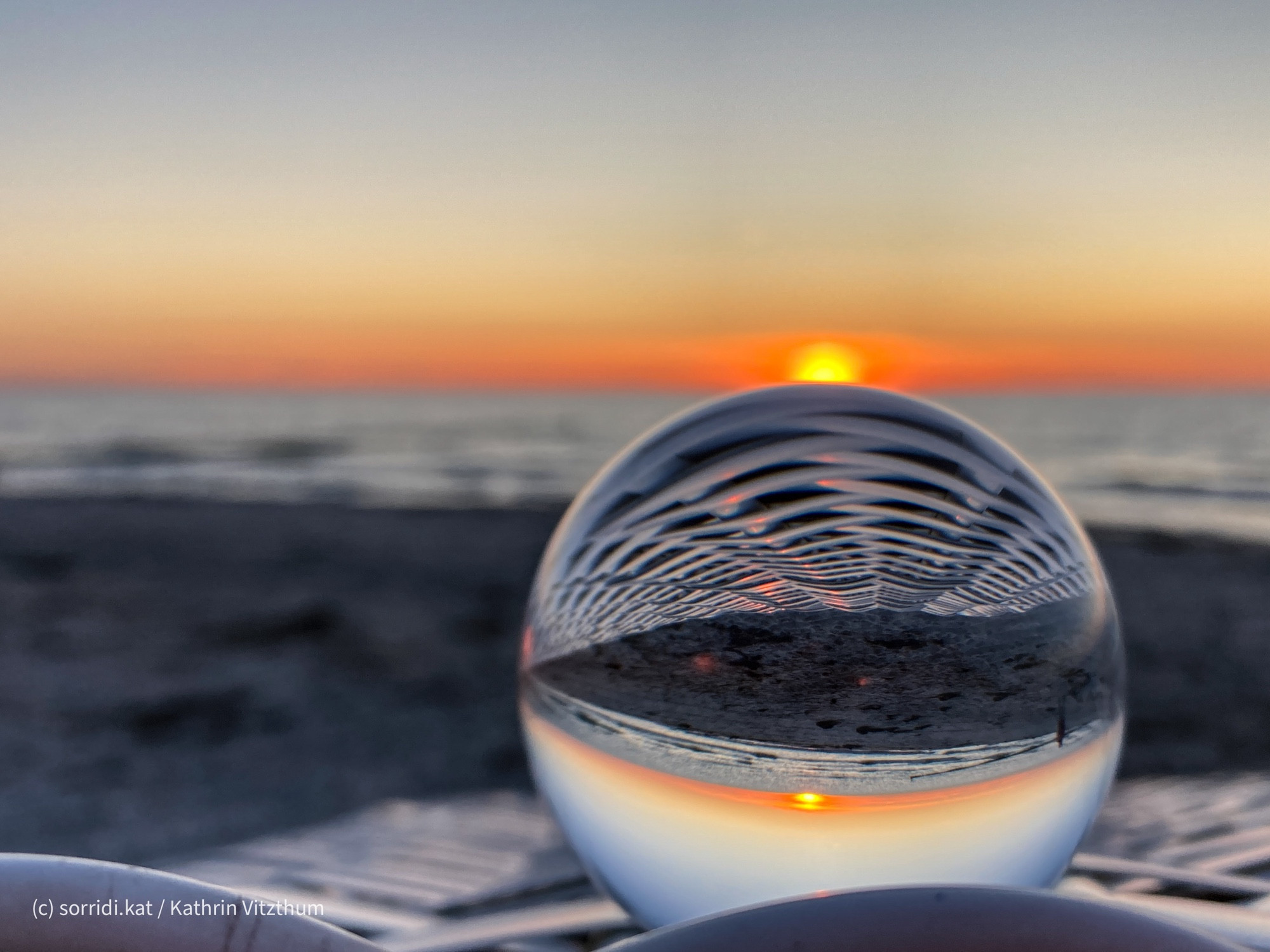 Lensball auf Strandkorb vor Sonnenuntergang.