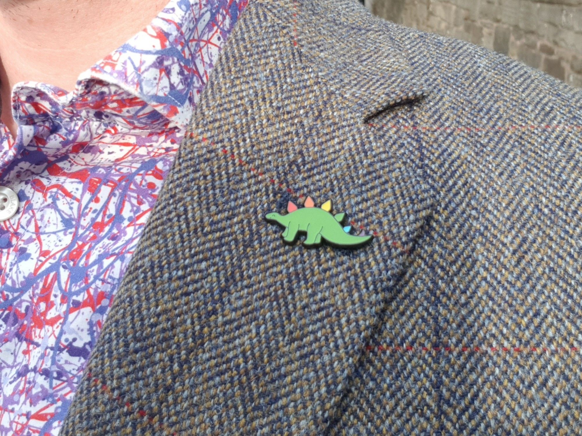 Stegosaurus pin badge on my lapel. The plates along its back are in the colours of the rainbow.