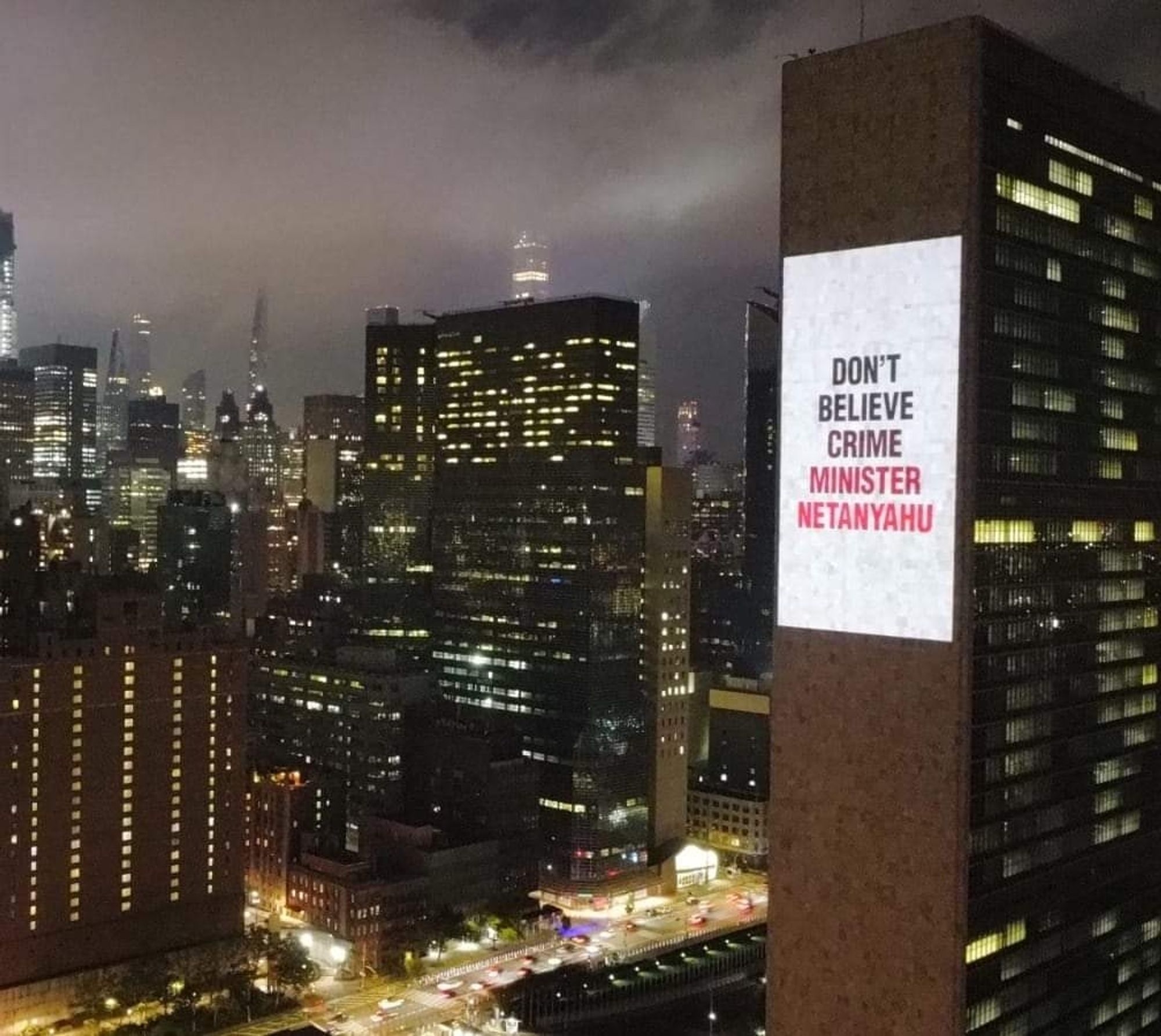 The UN building in New York City, with a project message "don't believe crime minister Netanyahu".