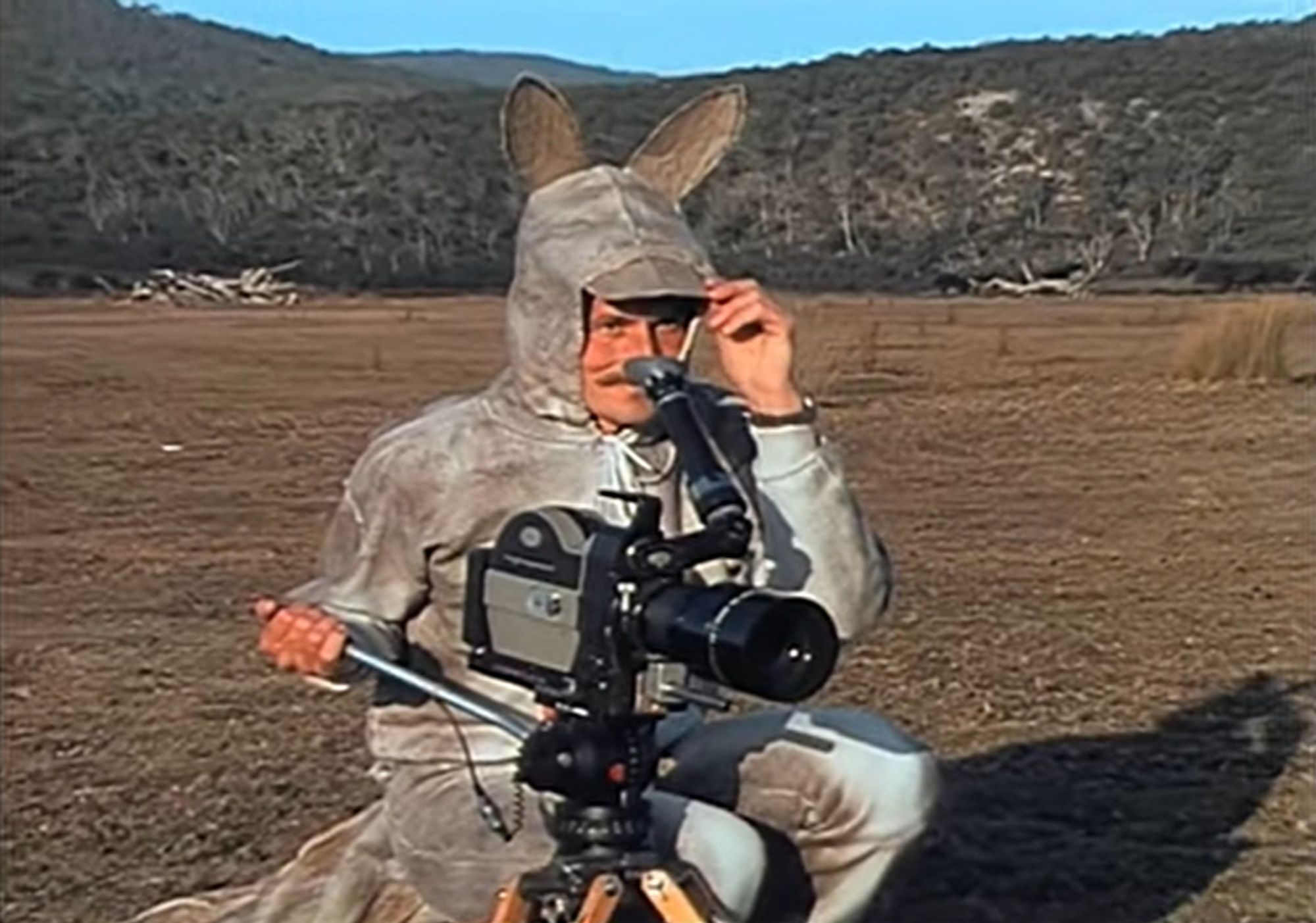 An image of a man with a mustache with a camera in a bad kangaroo costume.