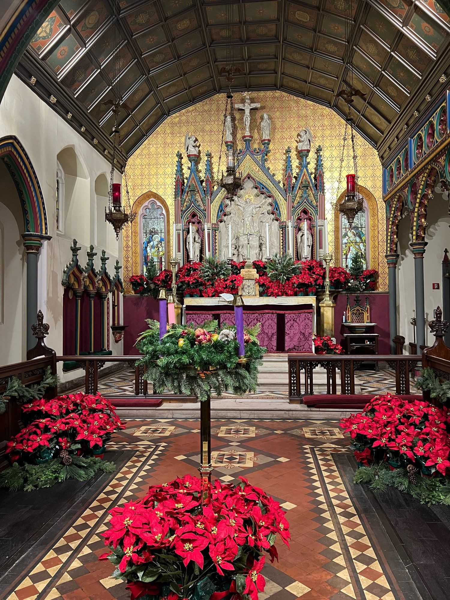 Purple Altar & Advent Wreath surrounded by red flowers.