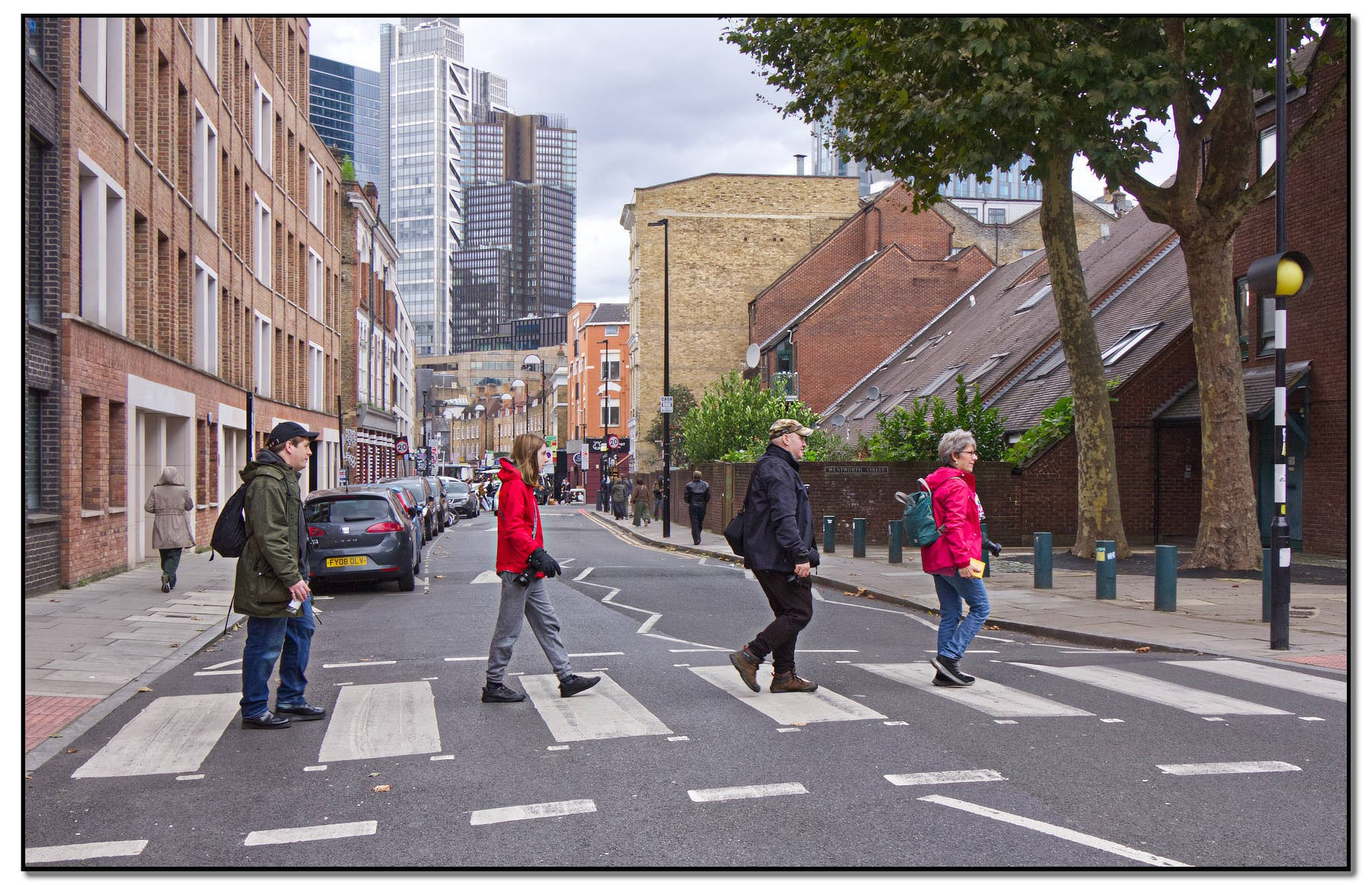 Colour photograph of four people walking over a zebra crossing in the style of the Beatles "Abbey Road" album cover.