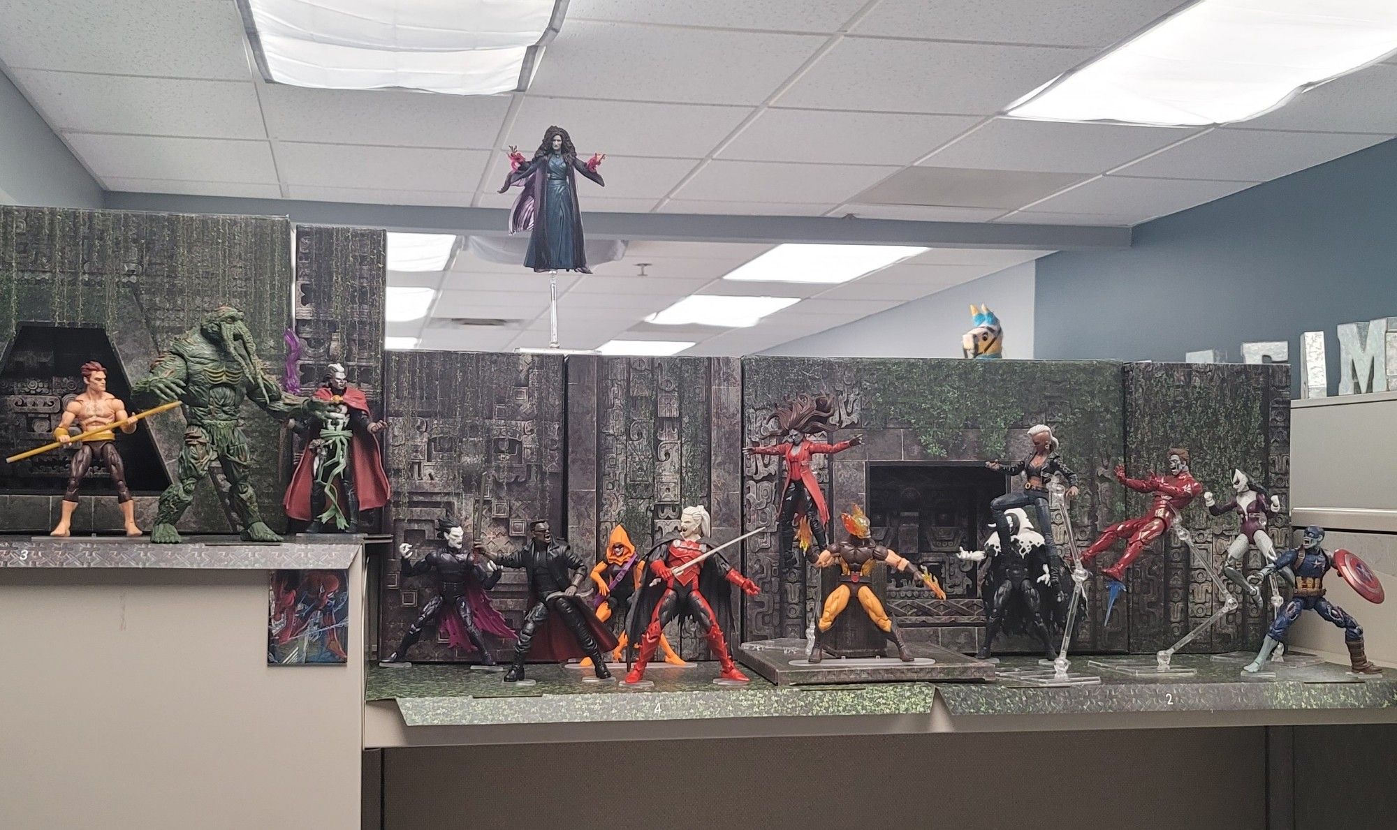 Wide view of a shelf of action figures, Daimon Hellstrom, Man-Thing, Brother Voodoo, Agatha Harkness, Morbius, Blade, Dracula, Hallows Eve, zombie Scarlrt Witch, Hellverine, Bloodstone, D'Sparye, zombie Iron Man, Lilith, and Zombie Captain America.