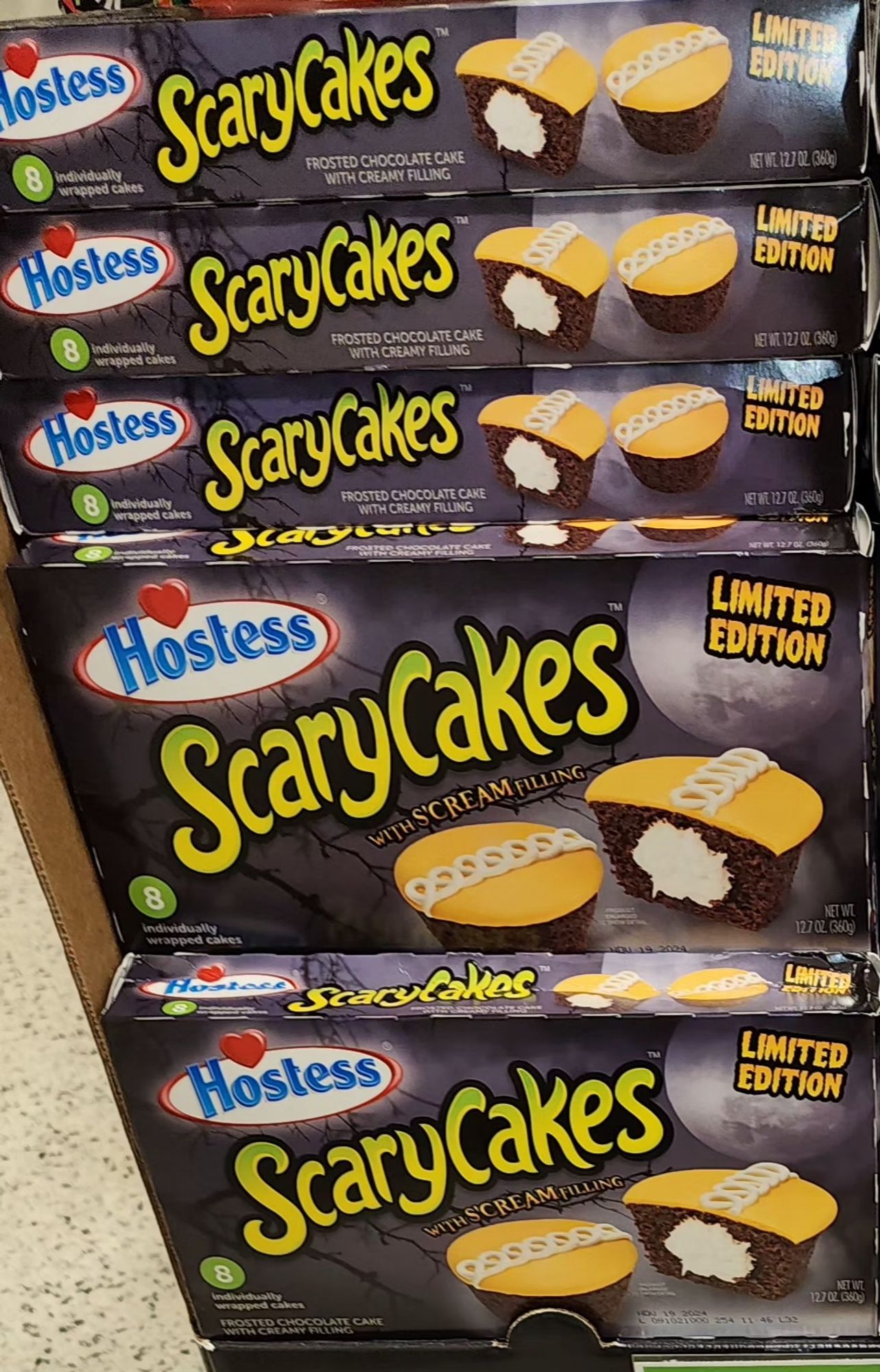 a box of hostess cakes labeled scary cakes limited edition. The box is black the word scary cakes is in green letter with black trim the word limited edition are orange letter with black trim and there are two traditional frosted with orange and white swirl hostess chocolate cakes on the box.