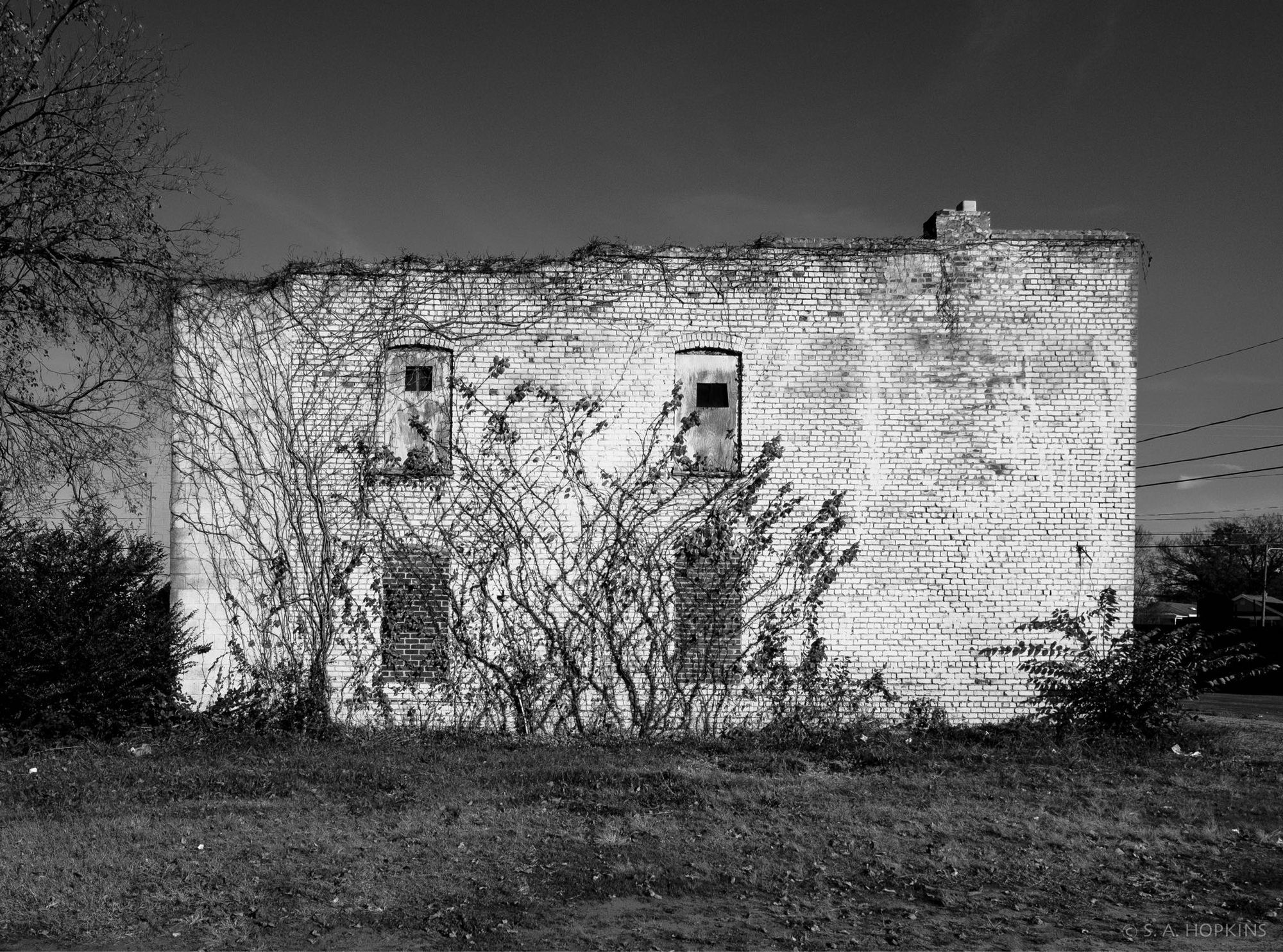 Black and white photograph showing the side of an old decaying brick building.